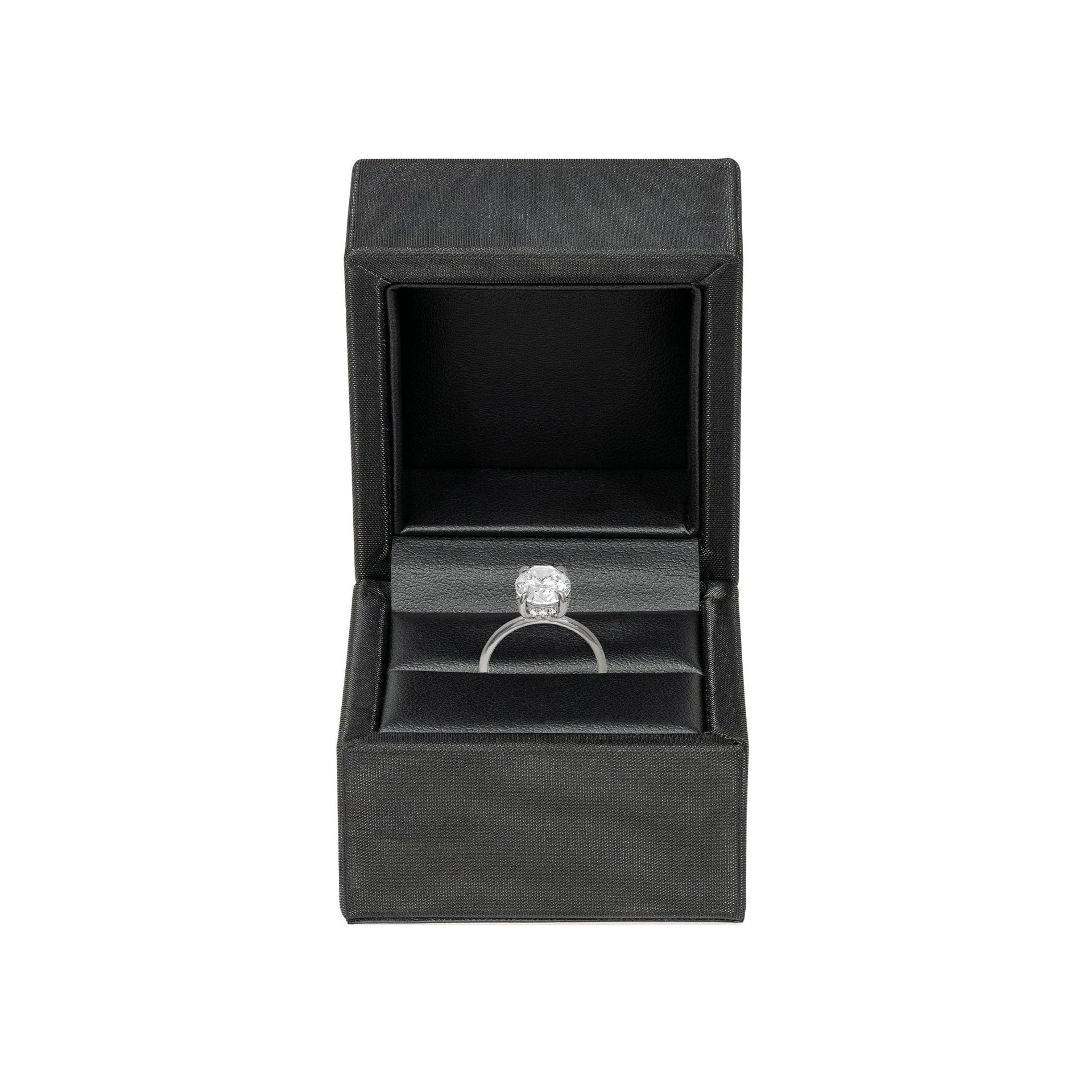 Black faux leather ring box shown in open position with silver engagement ring inside on a white background