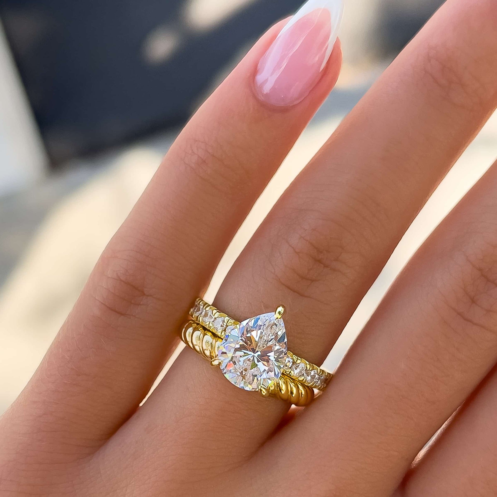 bold pear cut engagement ring paired with braided-style gold wedding band