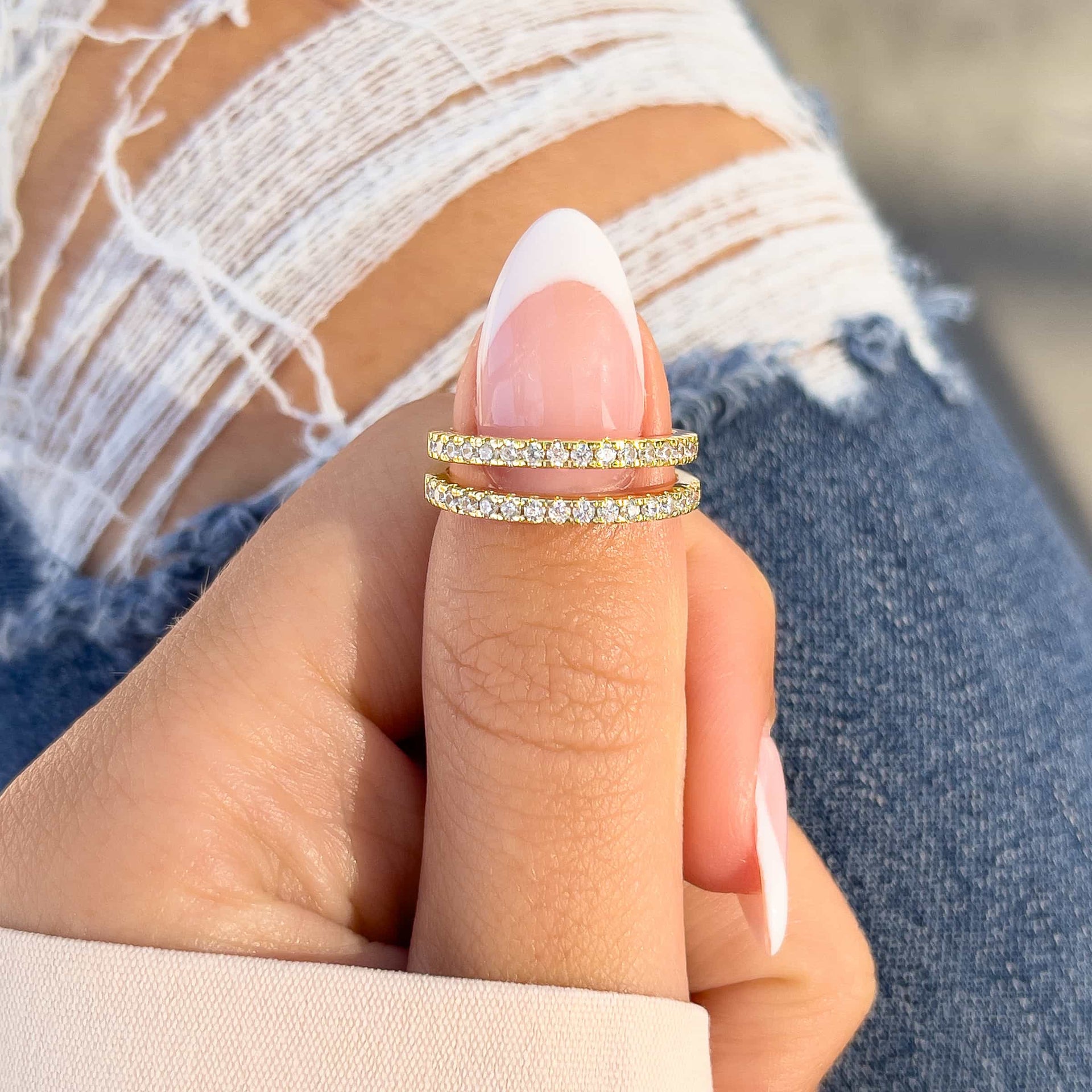 woman pinching two wedding bands together with jeans and cream top