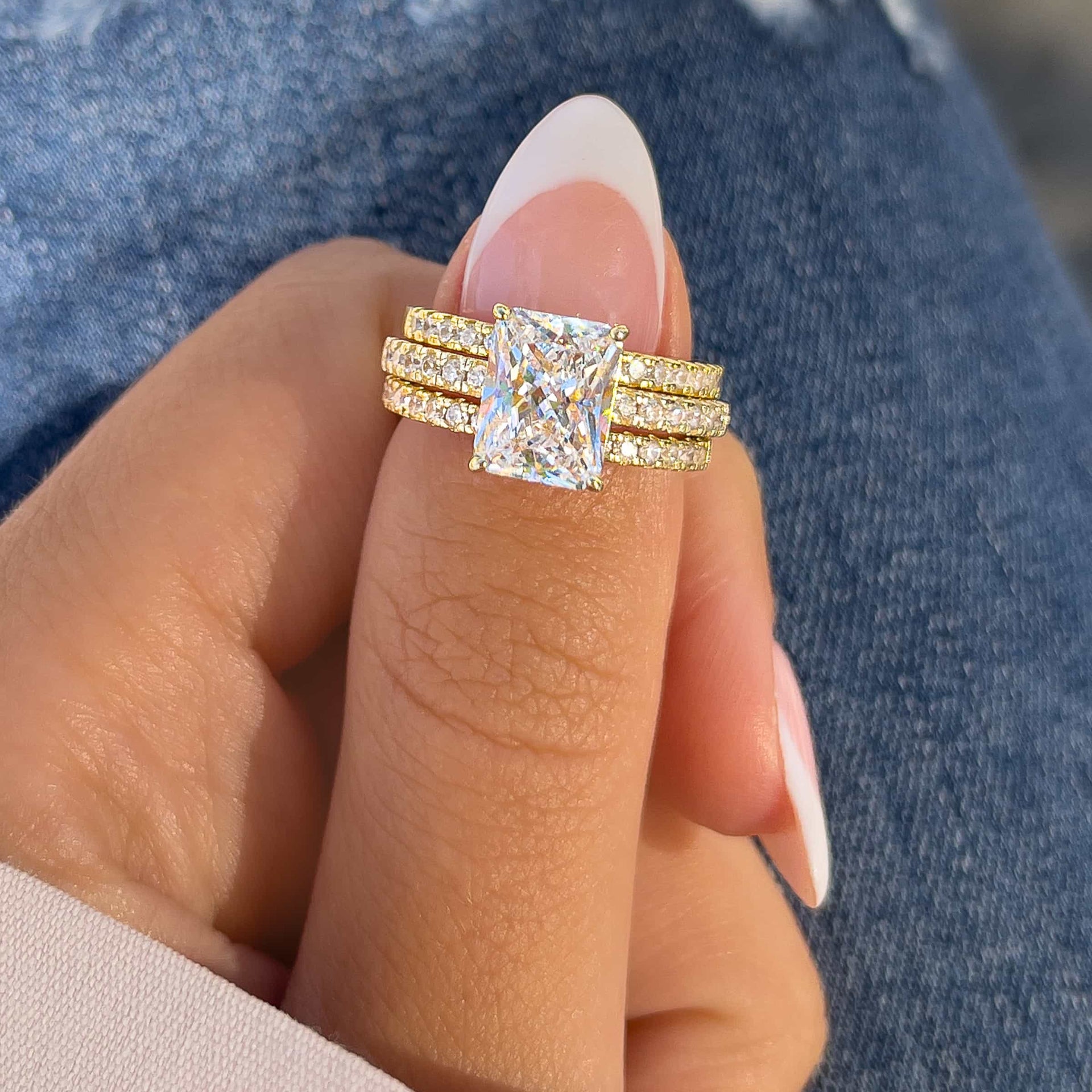 woman pinching wedding ring stack on thumb shown in gold