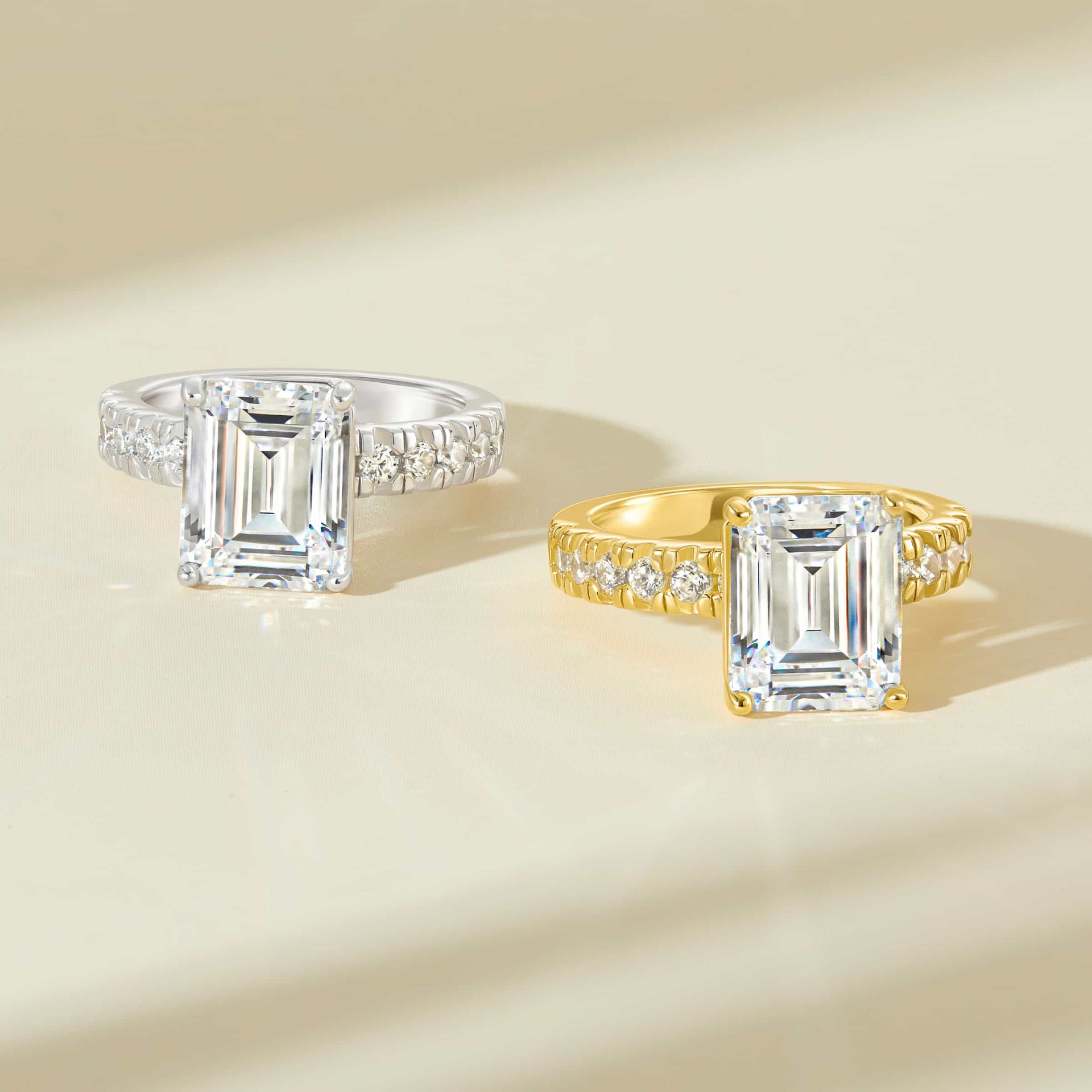 two 3.75 carat emerald cut engagement rings with half eternity band detailing shown in silver and gold