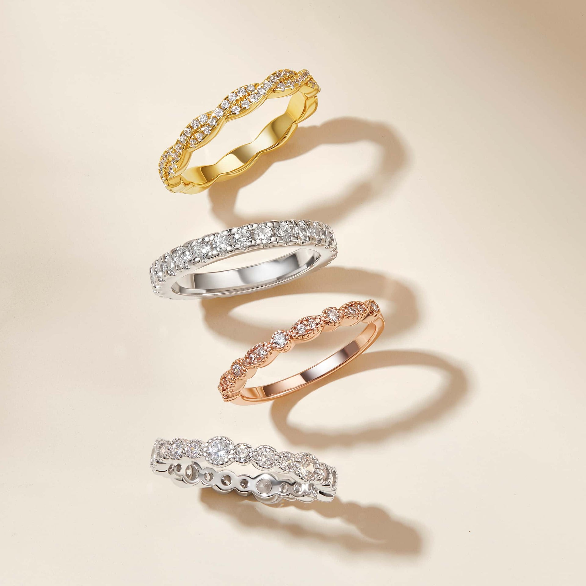 Gold, silver, and a rose gold wedding band all lined up on a light tan background