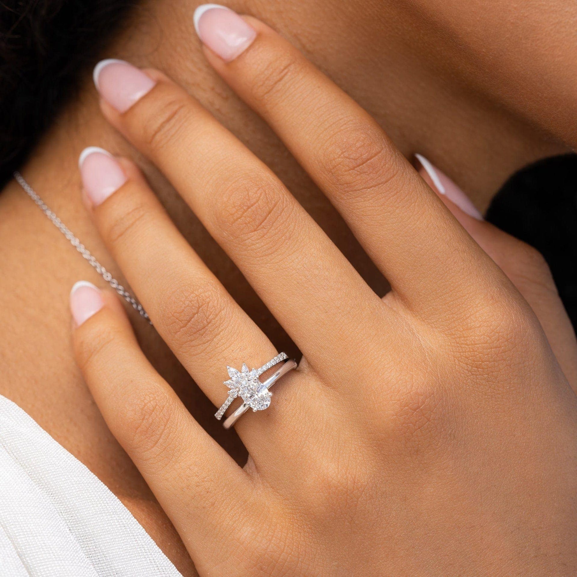 Silver wedding band stacked with oval solitaire on female hand