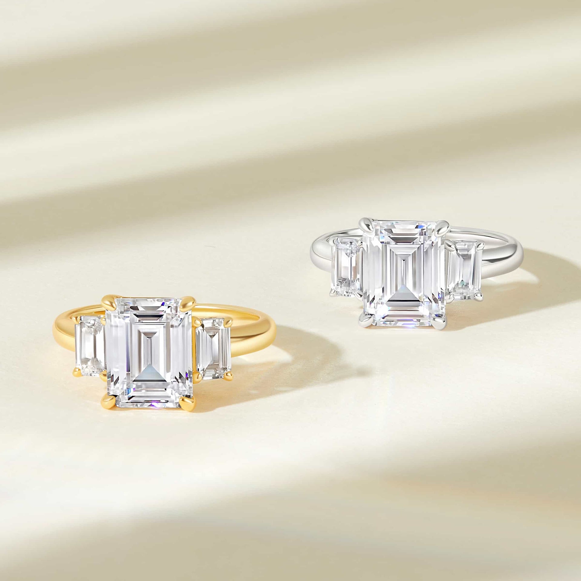 one gold and one silver stunning emerald cut trio wedding ring on cream background