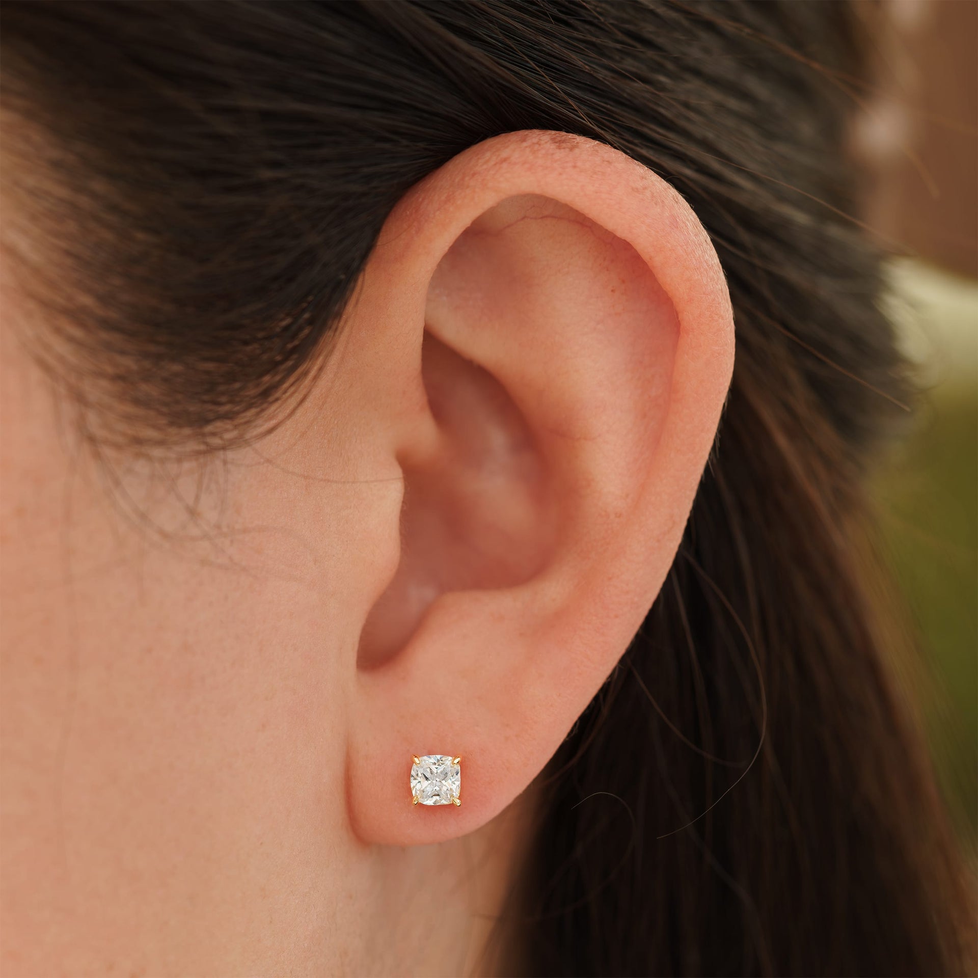 small gold cushion cut stud earrings on female model