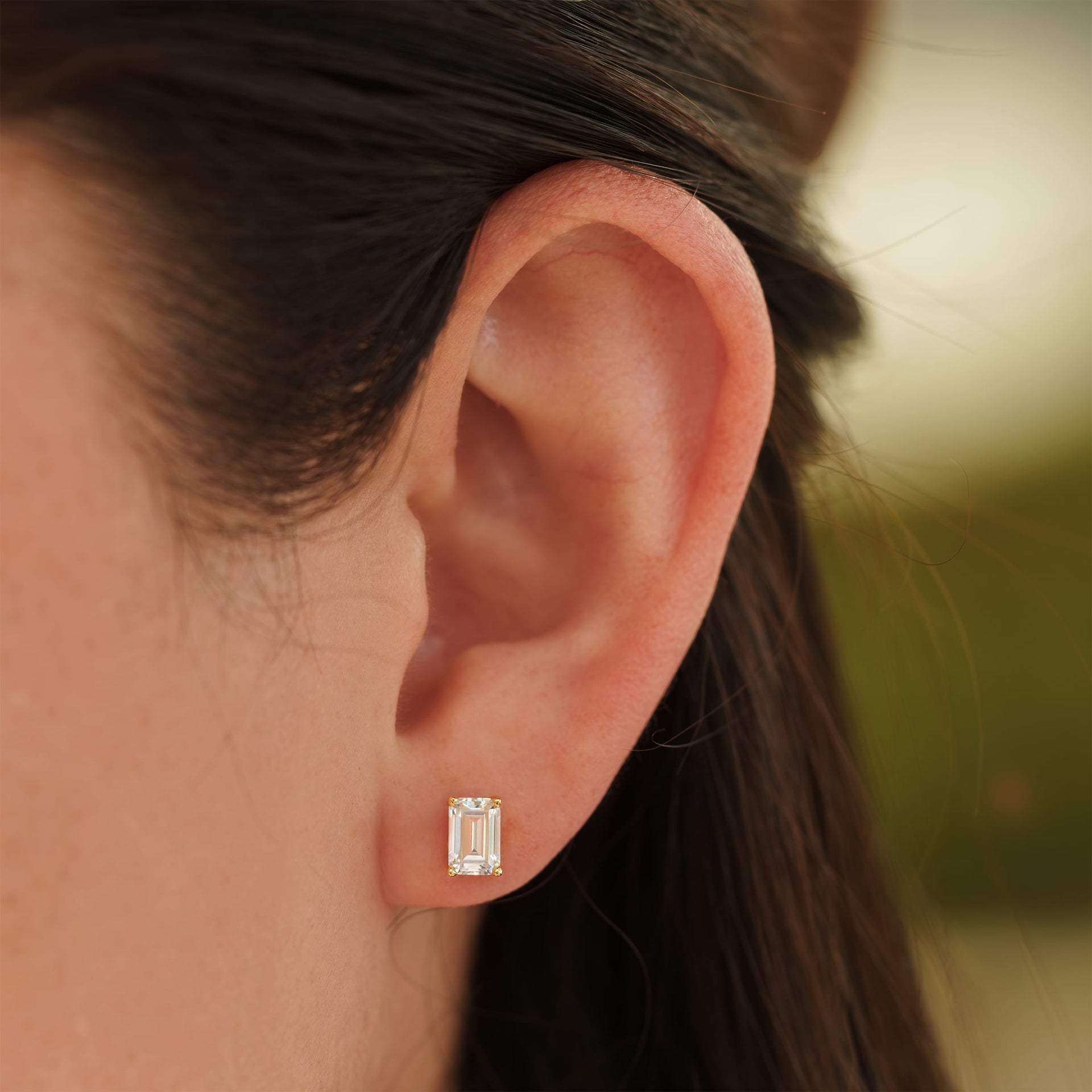 small gold emerald cut stud earrings on female model