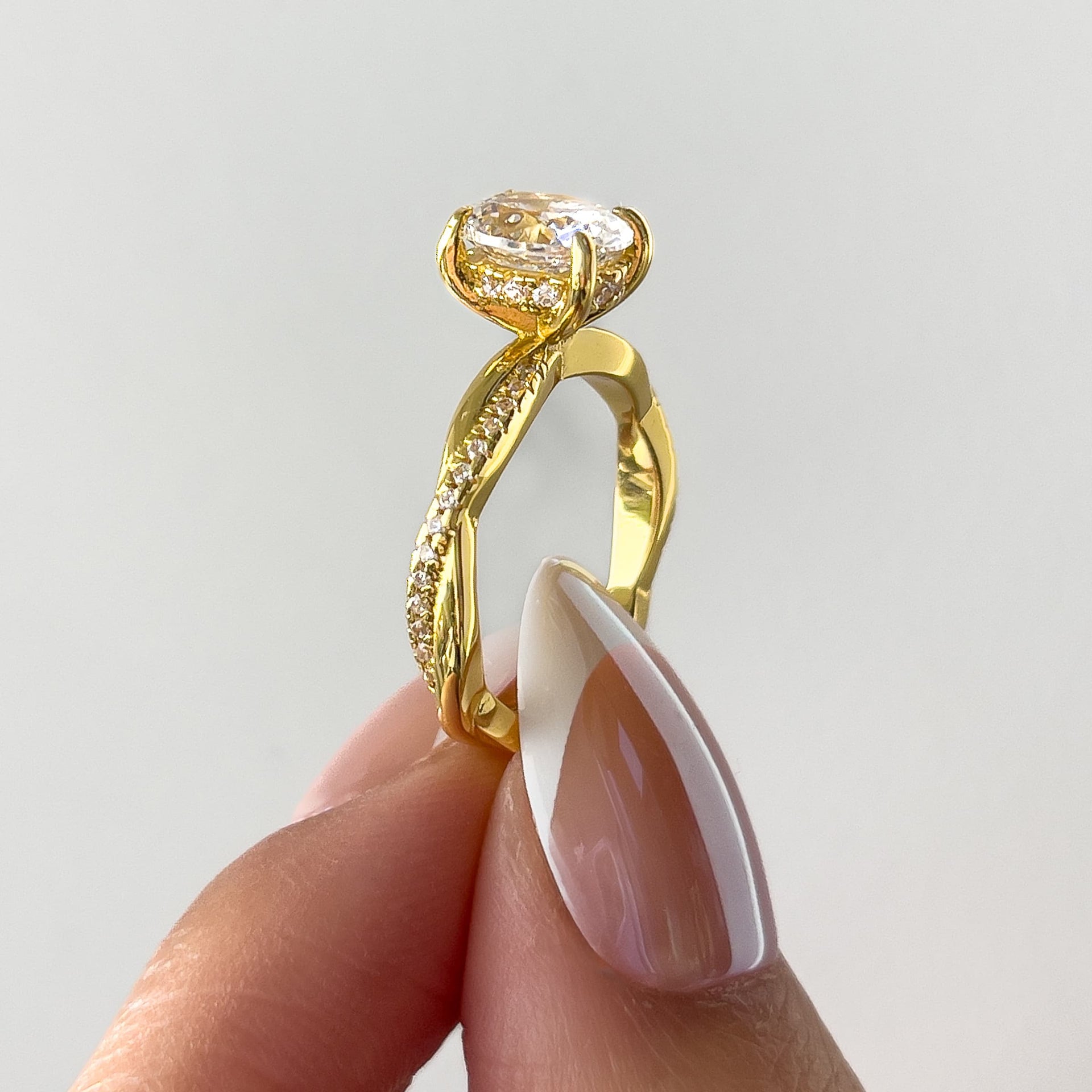side view of vintage gold 1.5 carat oval cut vintage ring held by model with french tip nails