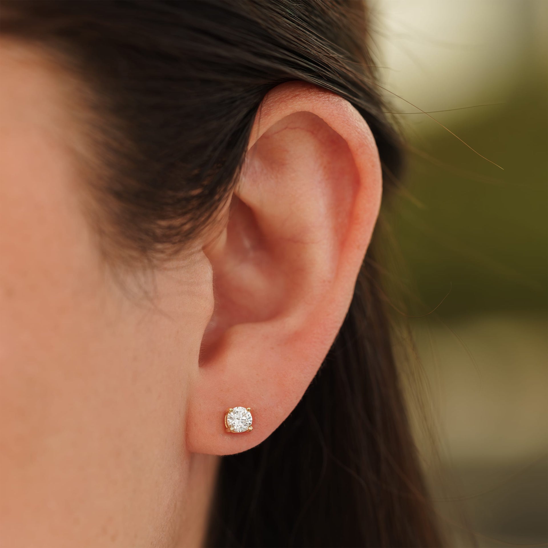 small gold round cut stud earrings on female model