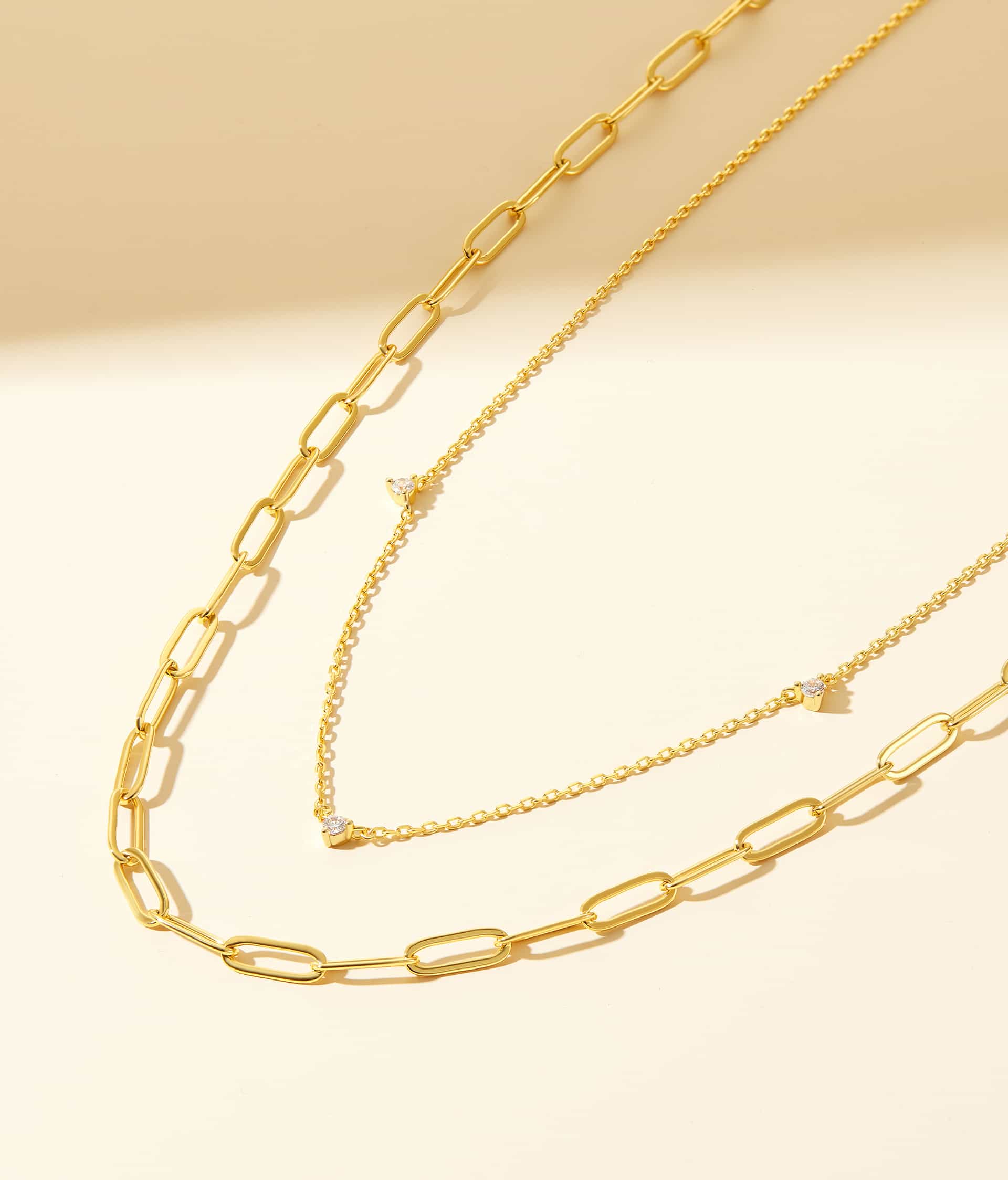 gold necklaces in stack with cream background