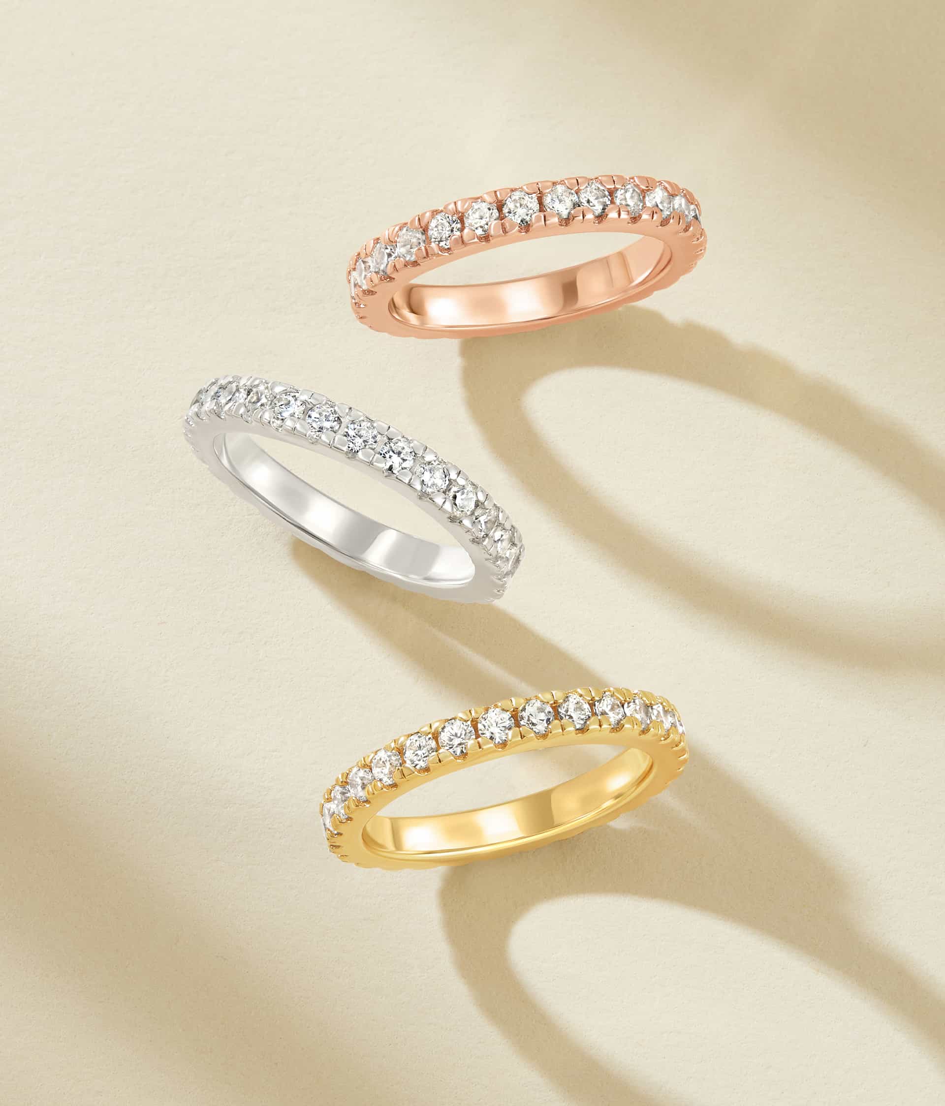 rose gold, silver, and gold wedding bands on cream background