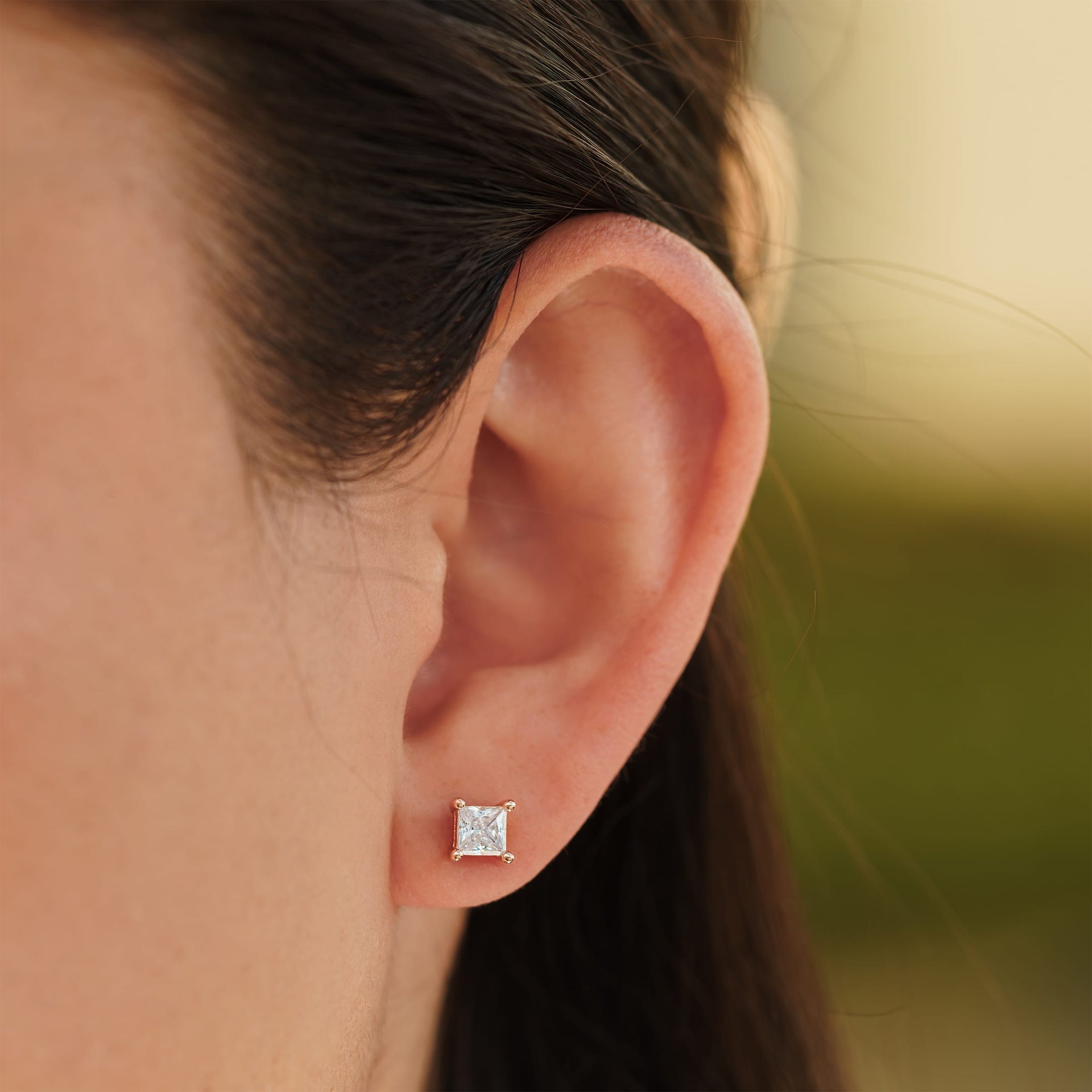 small rose gold princess cut stud earrings on female model