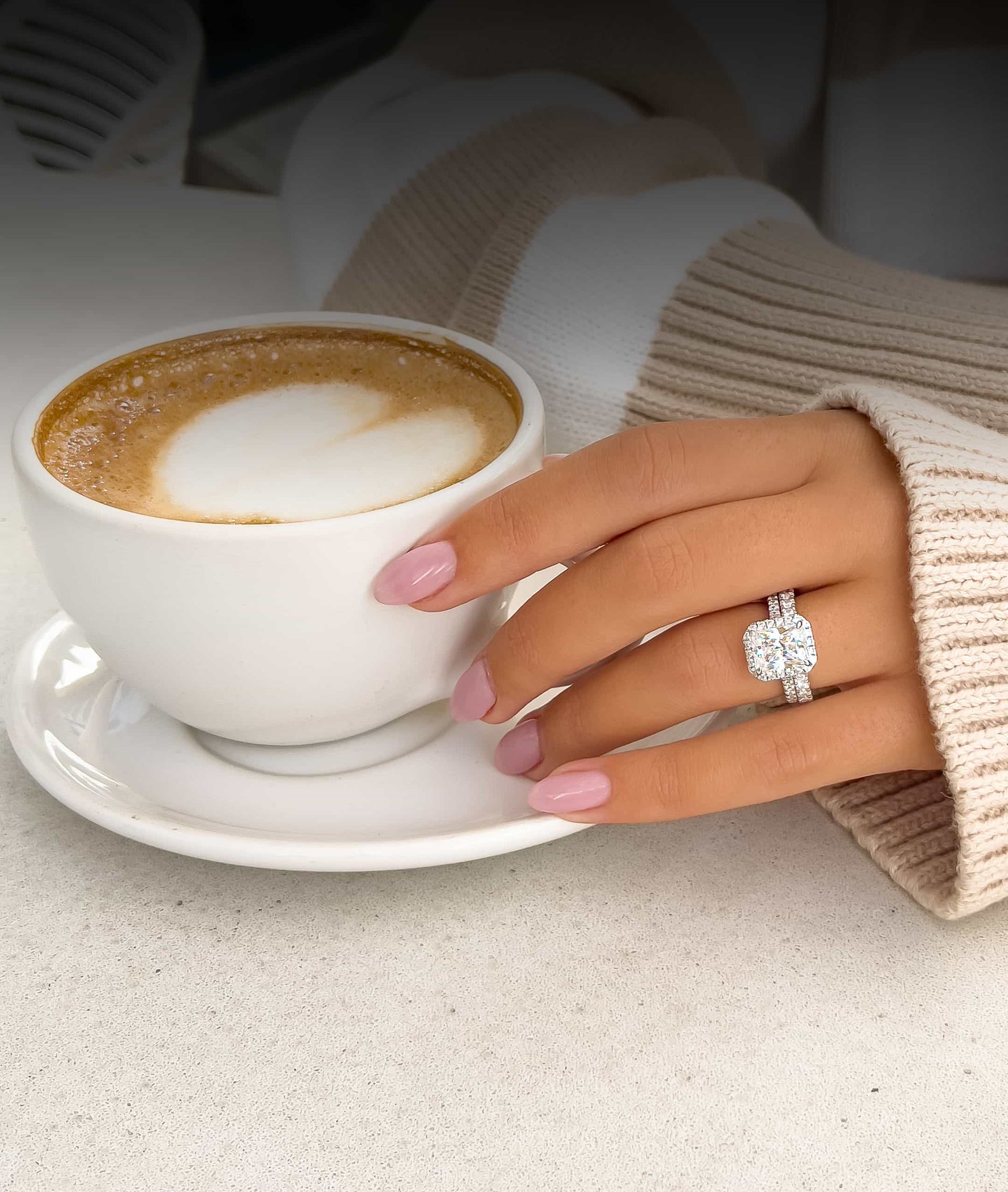 stunning silver radiant cut engagement ring with silver eternity band on ladies hand holding coffee