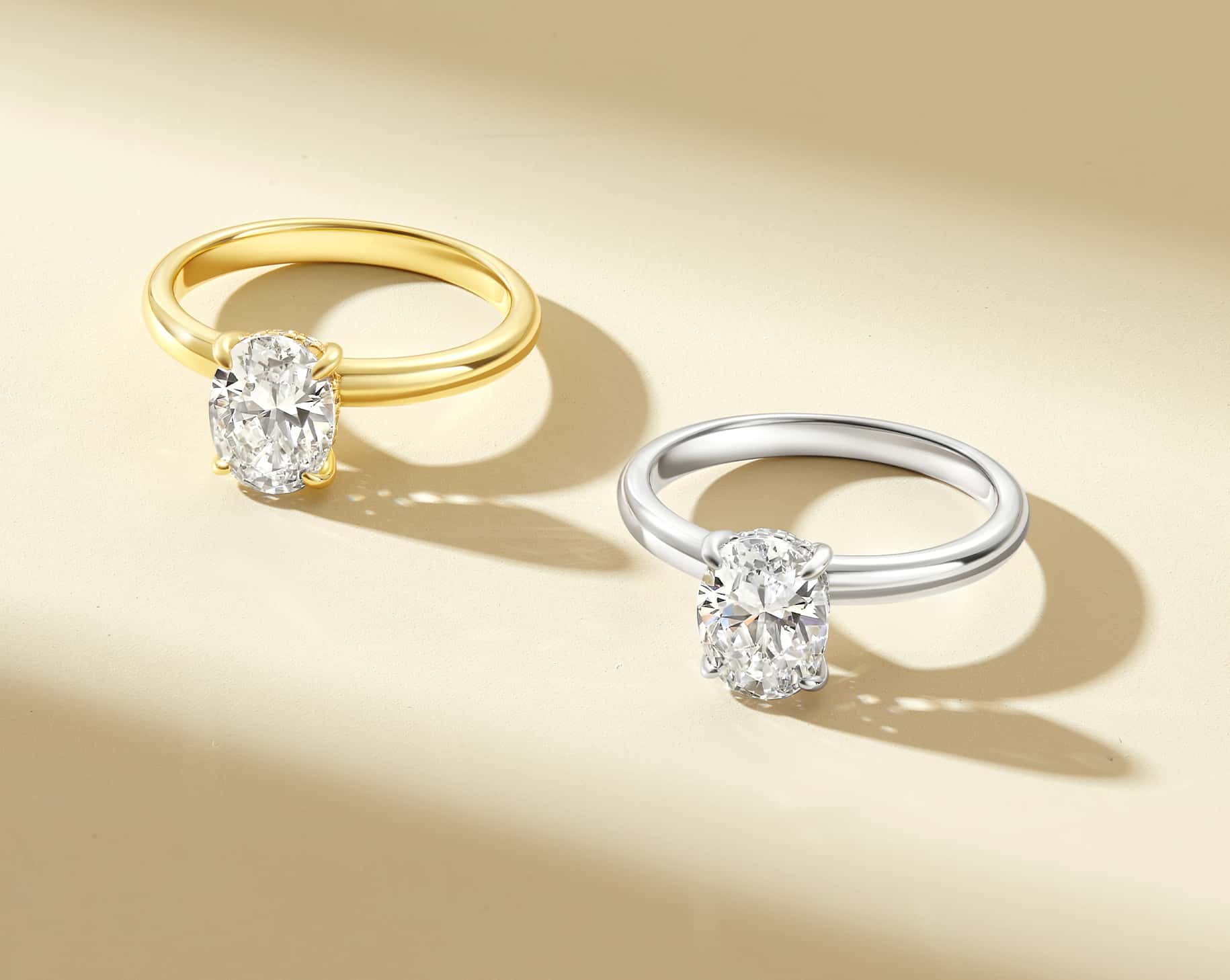 silver and gold solitaire oval engagement ring on warm background in a row