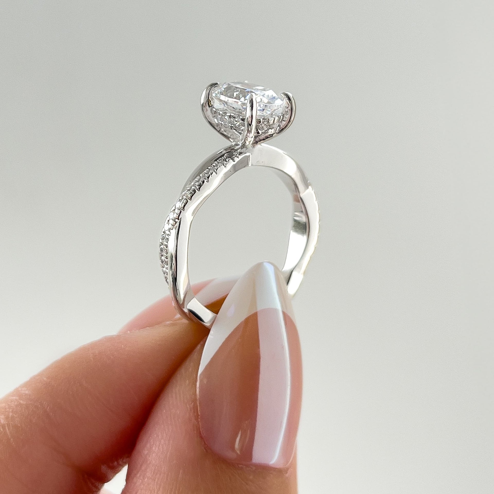side view of vintage silver 1.5 carat oval cut vintage ring held by model with french tip nails
