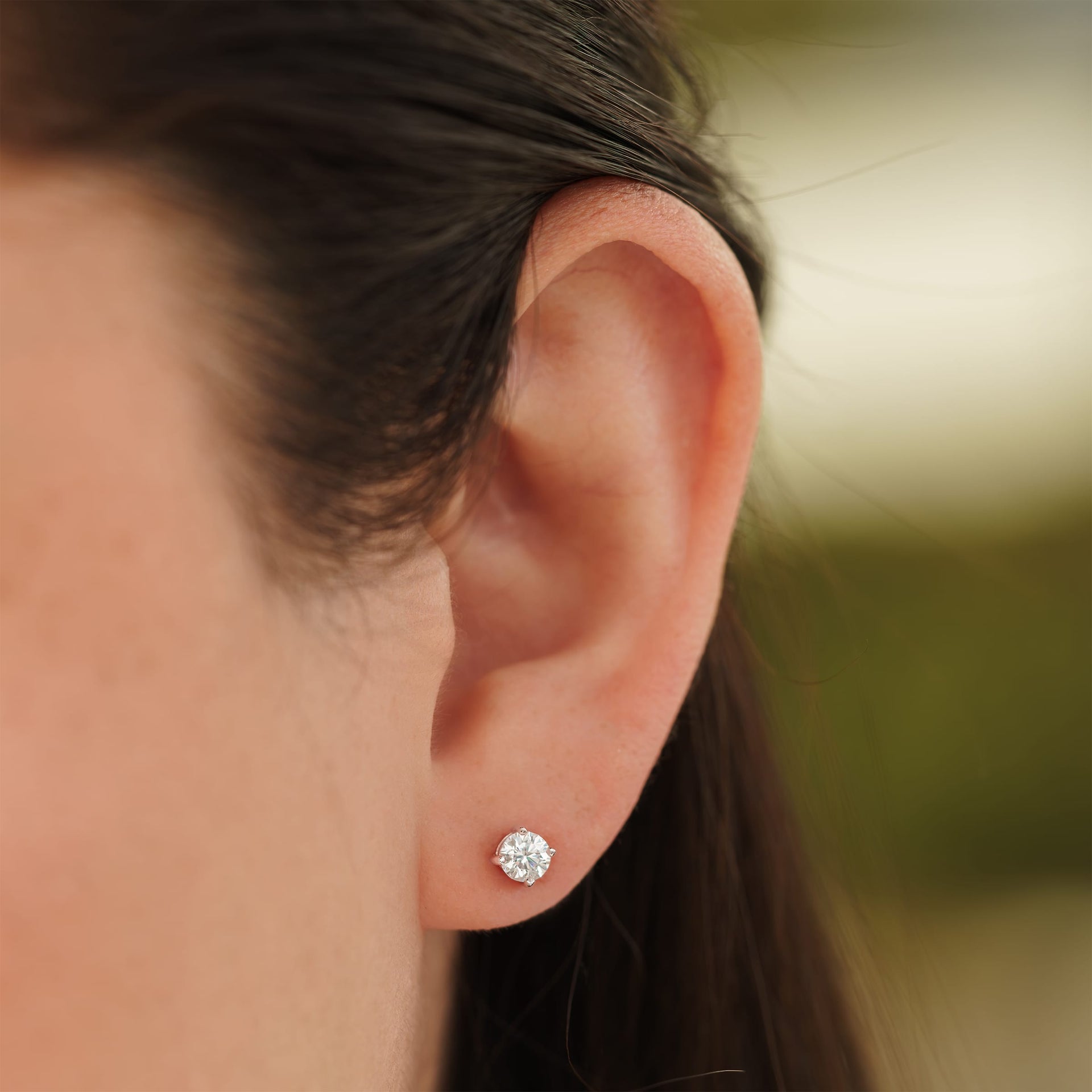 small silver round cut stud earrings on female model