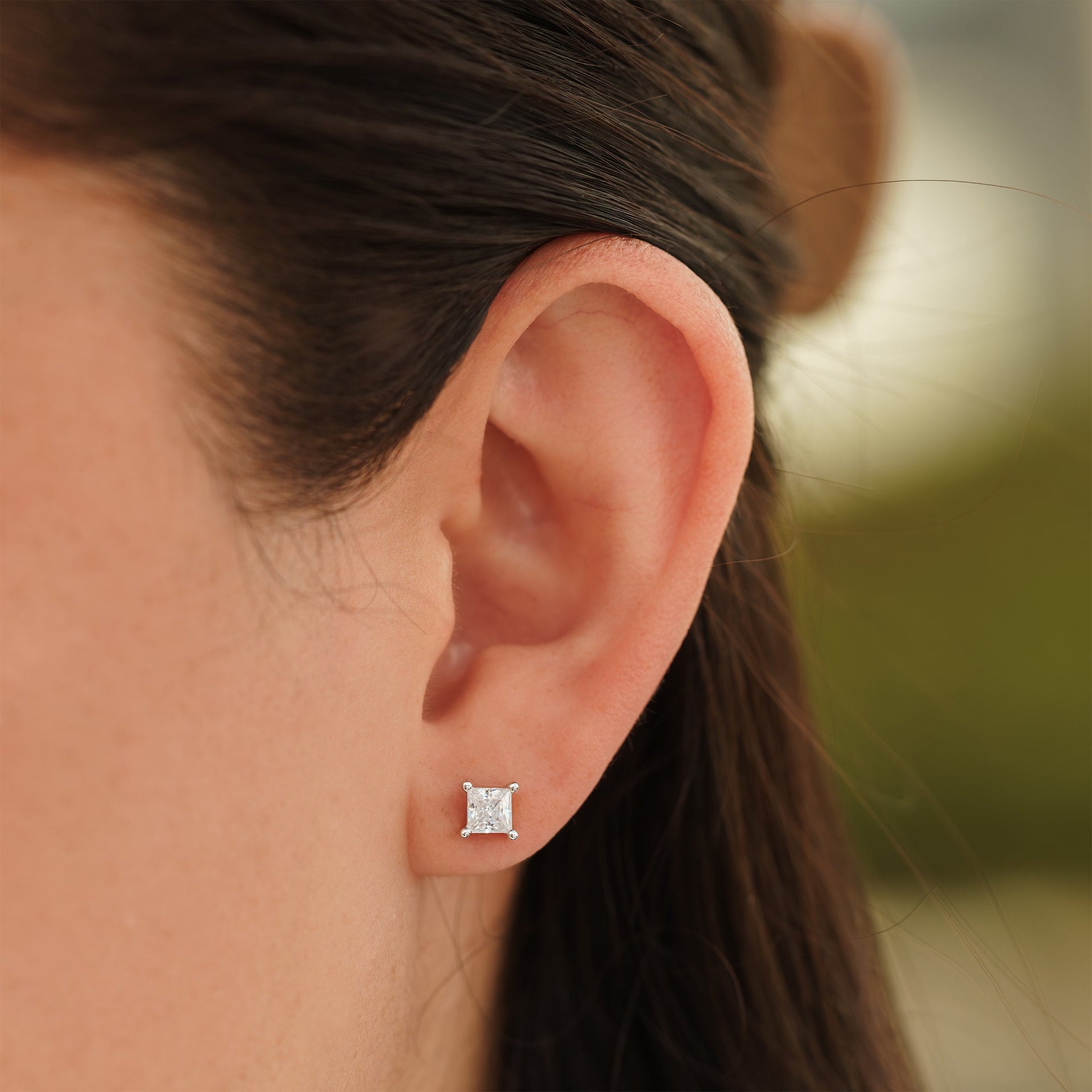 small silver princess cut stud earrings on female model