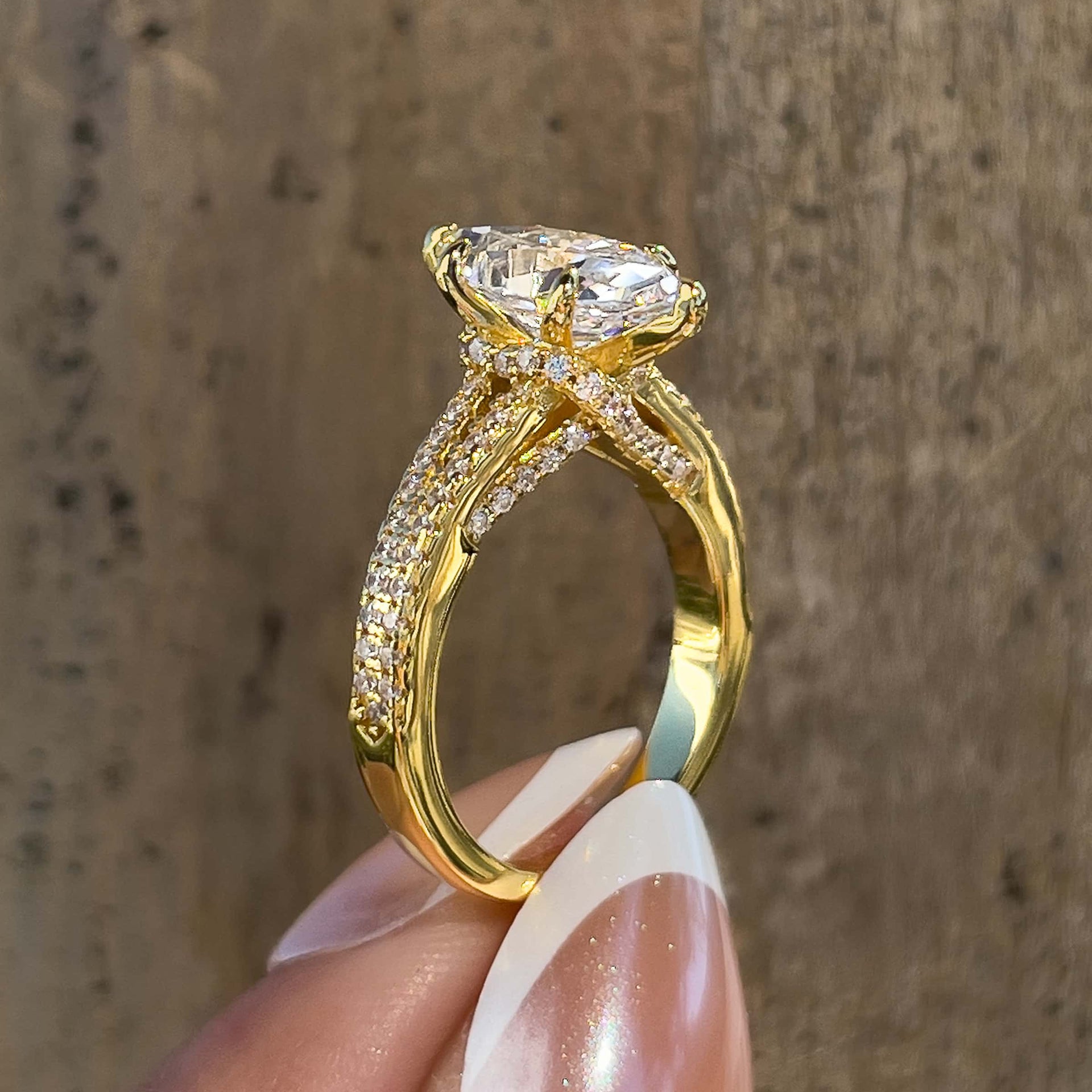Side view of gold vintage 2 carat marquise cut split shank engagement ring held by model with french tip nails