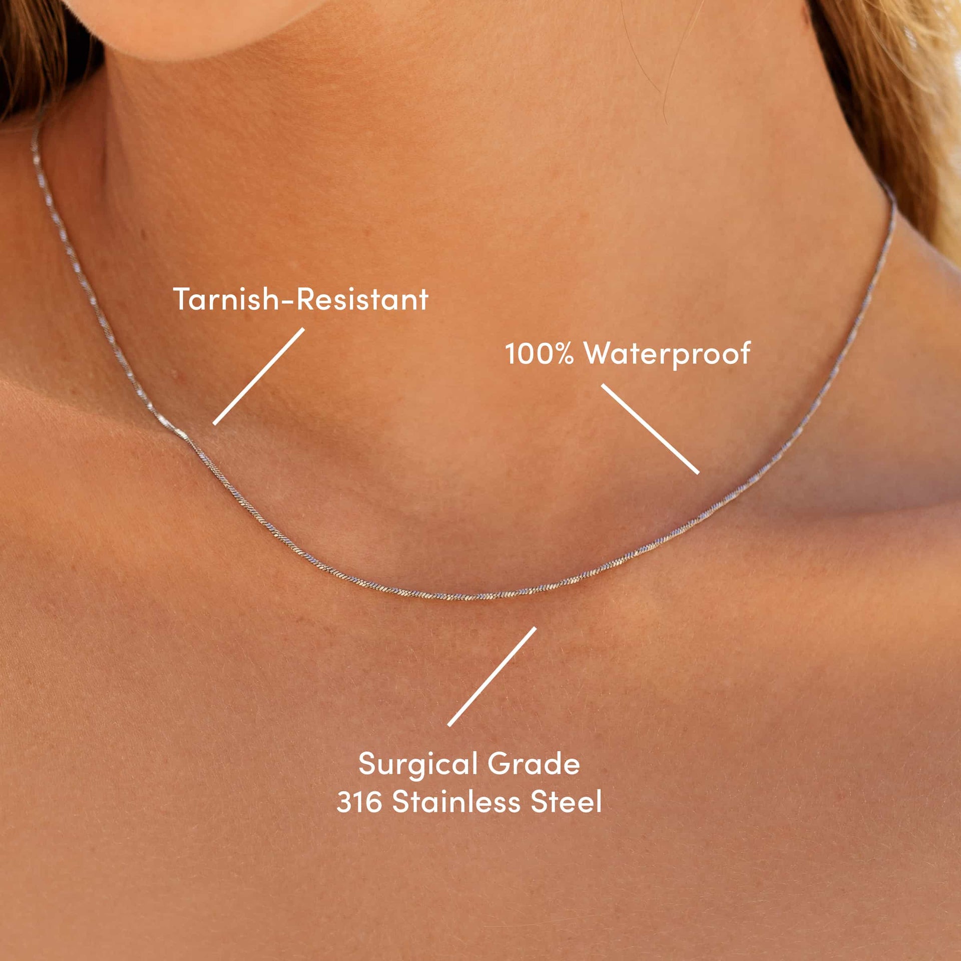 a silver stainless steel snake chain necklace worn by a model with the text overlayed "tarnish-resistant, 100% waterproof, surgical grade 316 stainless steel"