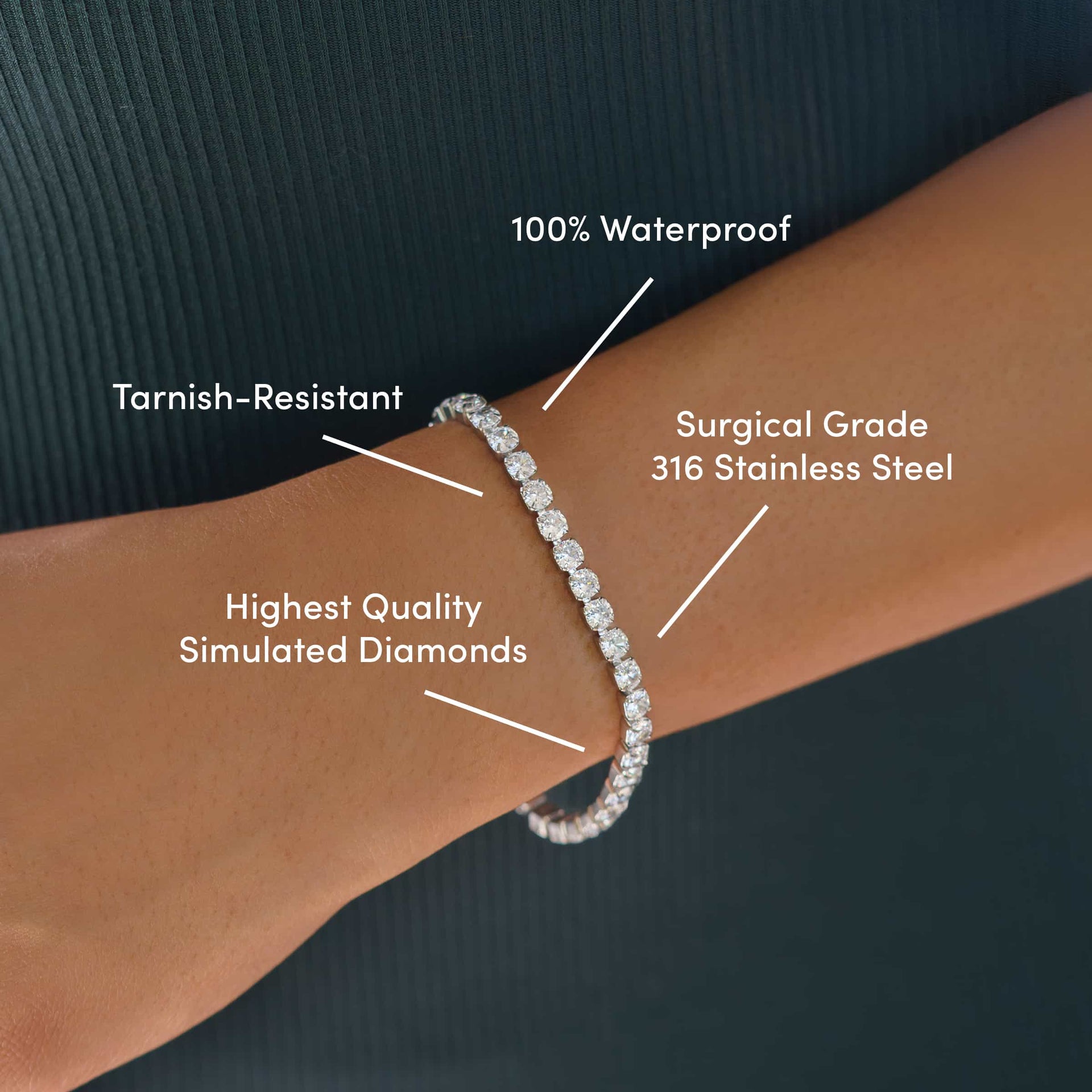 everyday silver tennis bracelet worn by model wearing dark colors with the text over it: Tarnish-Resistant, Surgical Grade 316 Stainless Steel, Highest Quality Simulated Diamonds, 100% Waterproof