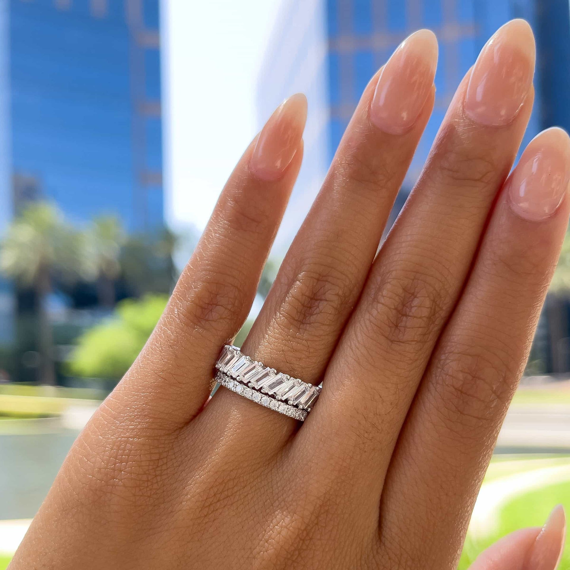 silver bold baguette band and a smaller eternity band on model with neutral nails