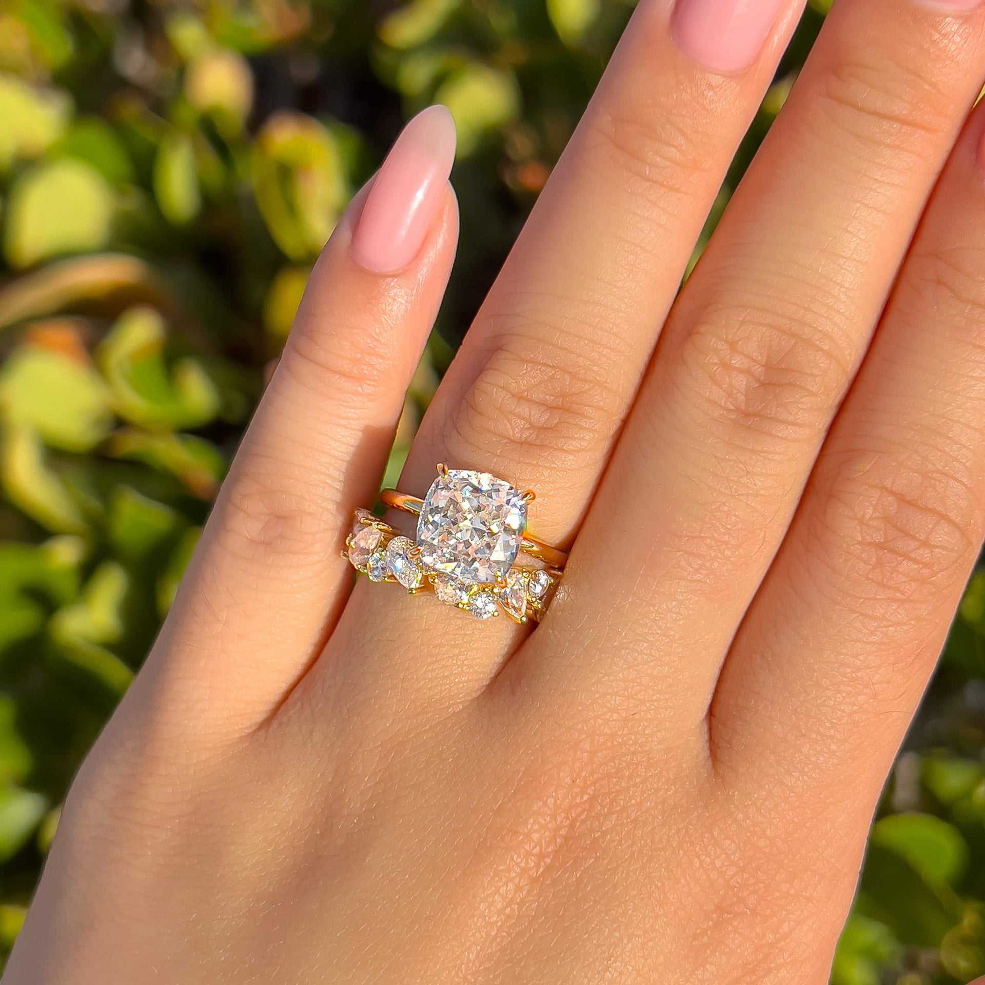 gorgeous wedding set worn by model with a gold cushion cut solitaire engagement ring and bold mixed cut wedding band