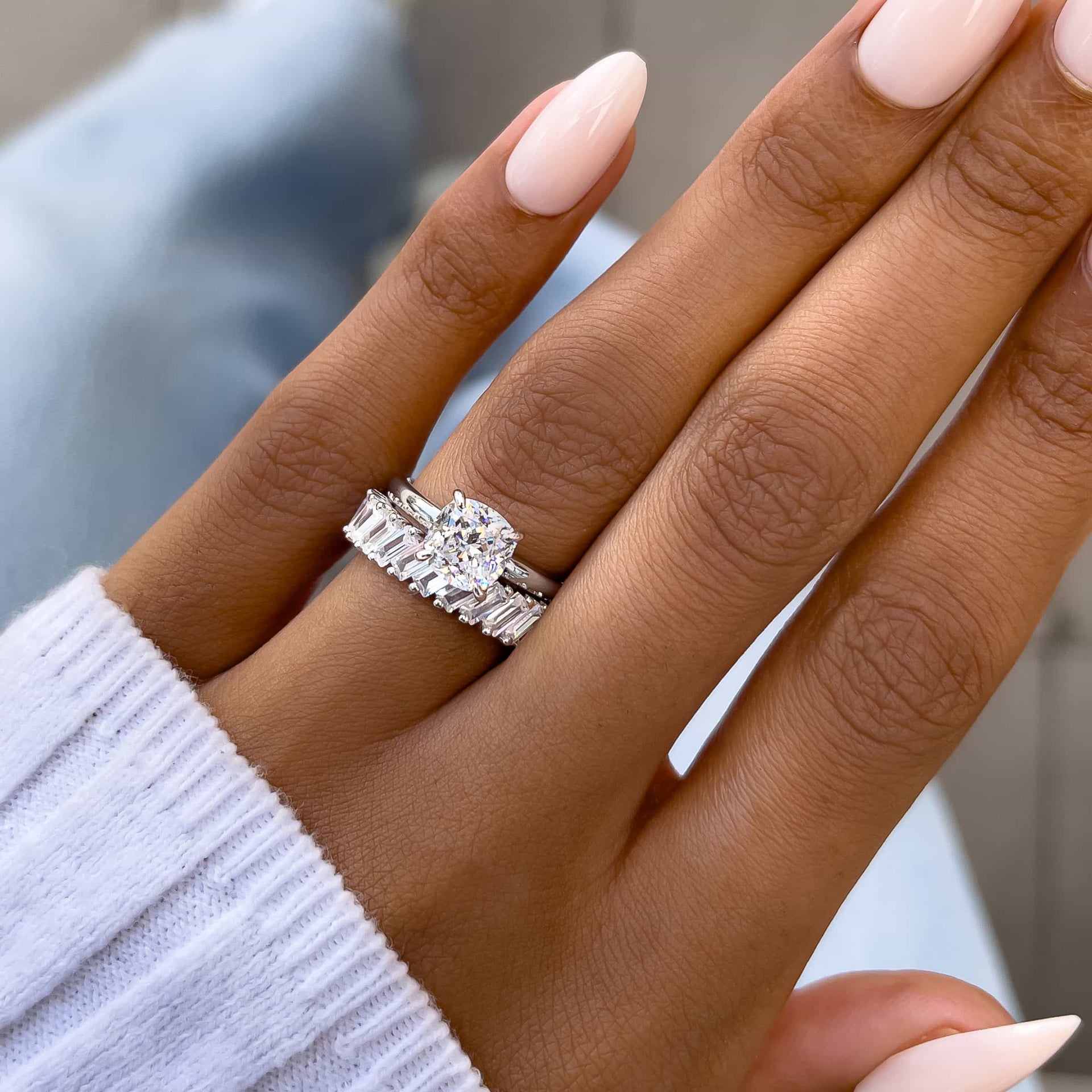 gorgeous silver 1.5 carat wedding ring set completed with cushion cut solitaire engagement ring and silver baguette statement band on model with neutral nails and white sweater