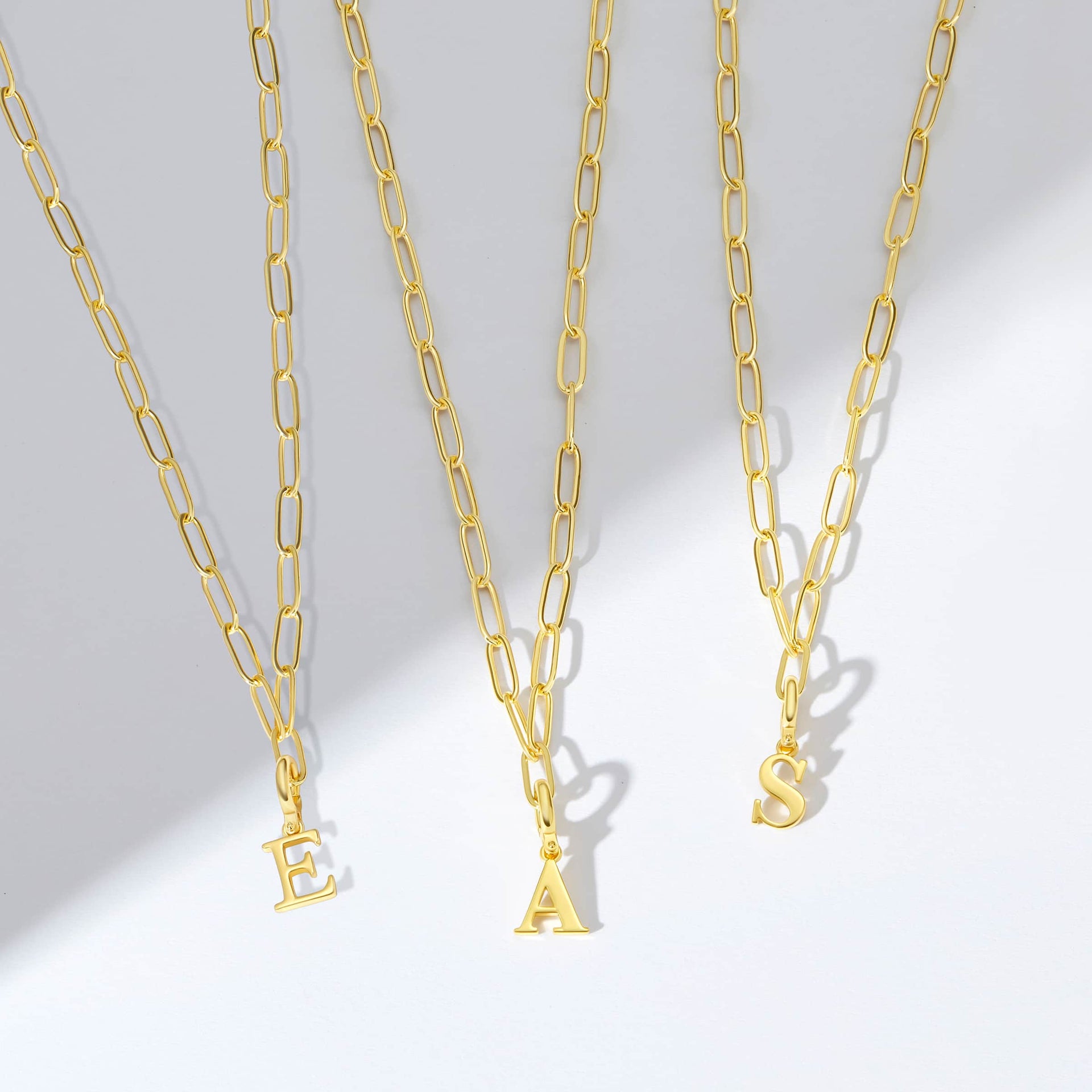 the gold letter charms shown in "E", "A", and "S" on gold necklaces