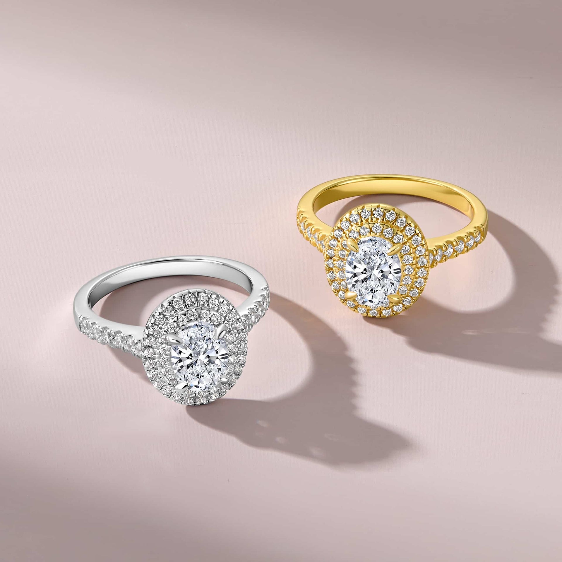 1.5 carat oval cut double halo half eternity engagement ring in silver and gold on a neutral/pink background