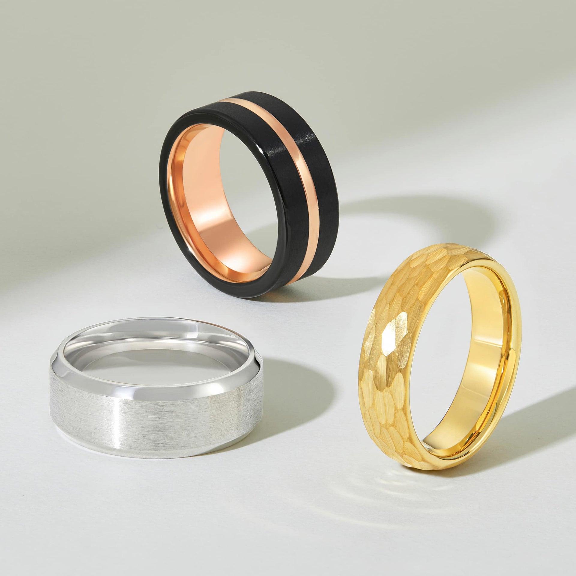 black and rose gold mens wedding band shown with a silver and a gold wedding band below it