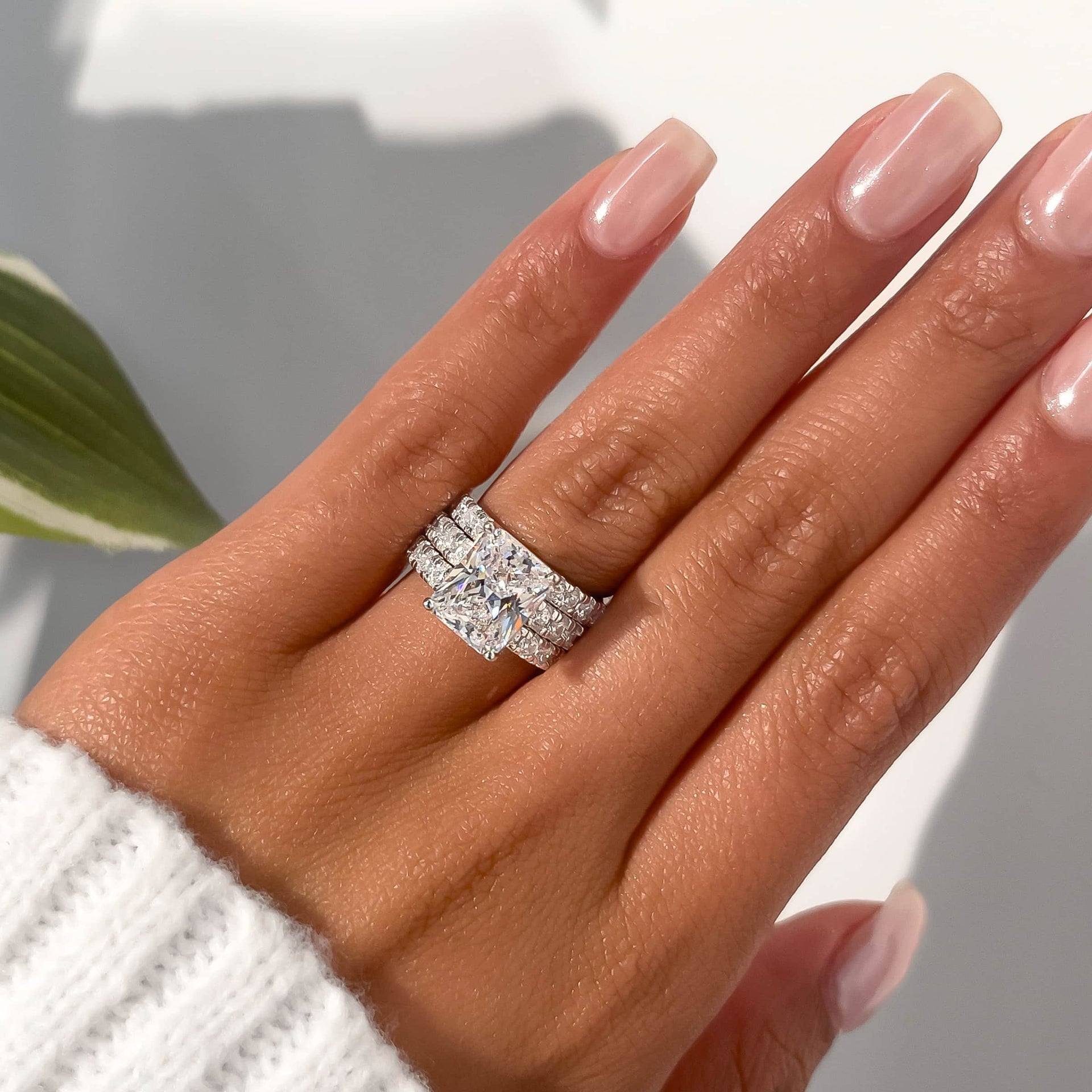 silver radiant cut half eternity engagement ring with matching half eternity bands on model with white sweater