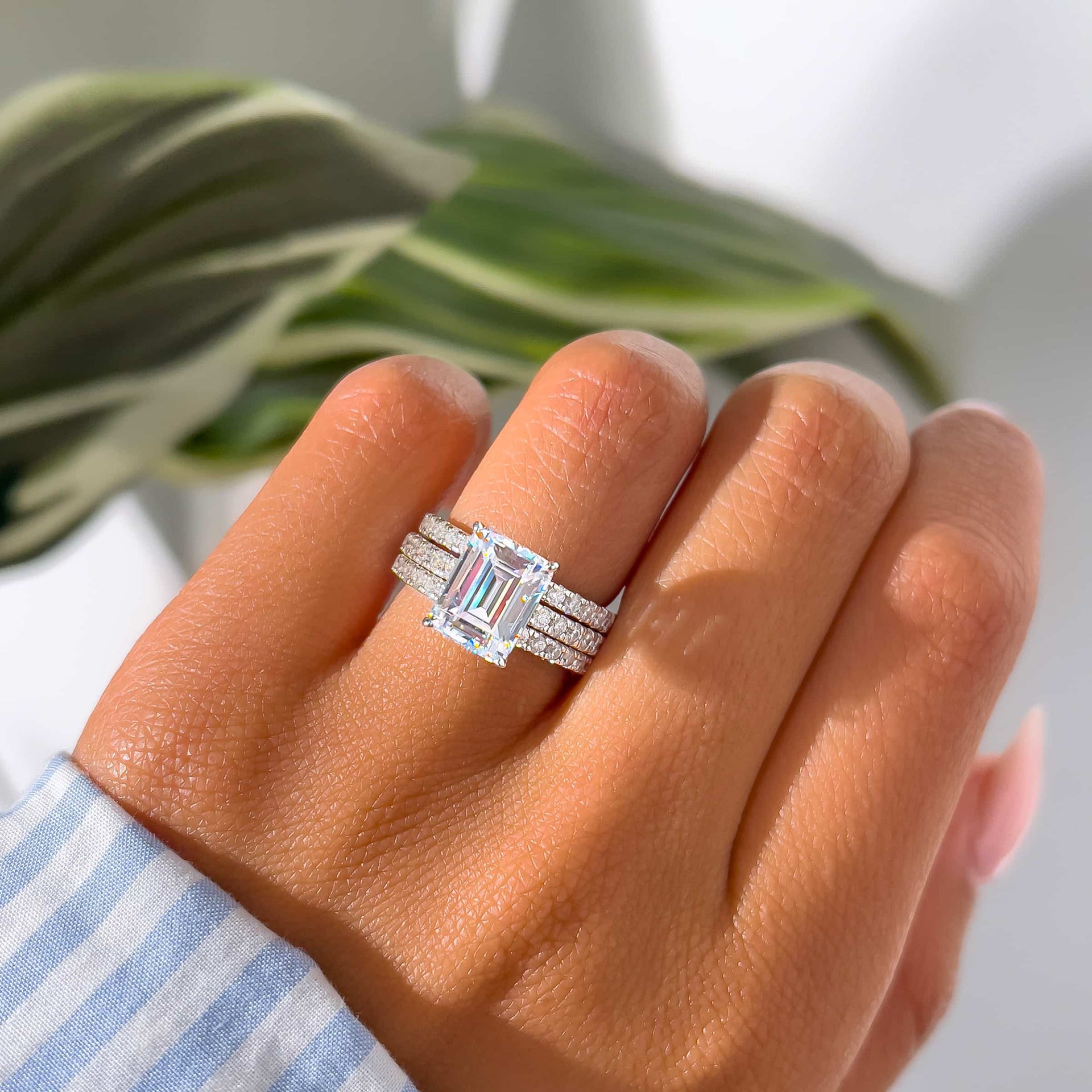 silver 3 carat emerald cut engagement ring stacked with two wedding bands on both sides modeled on female hand