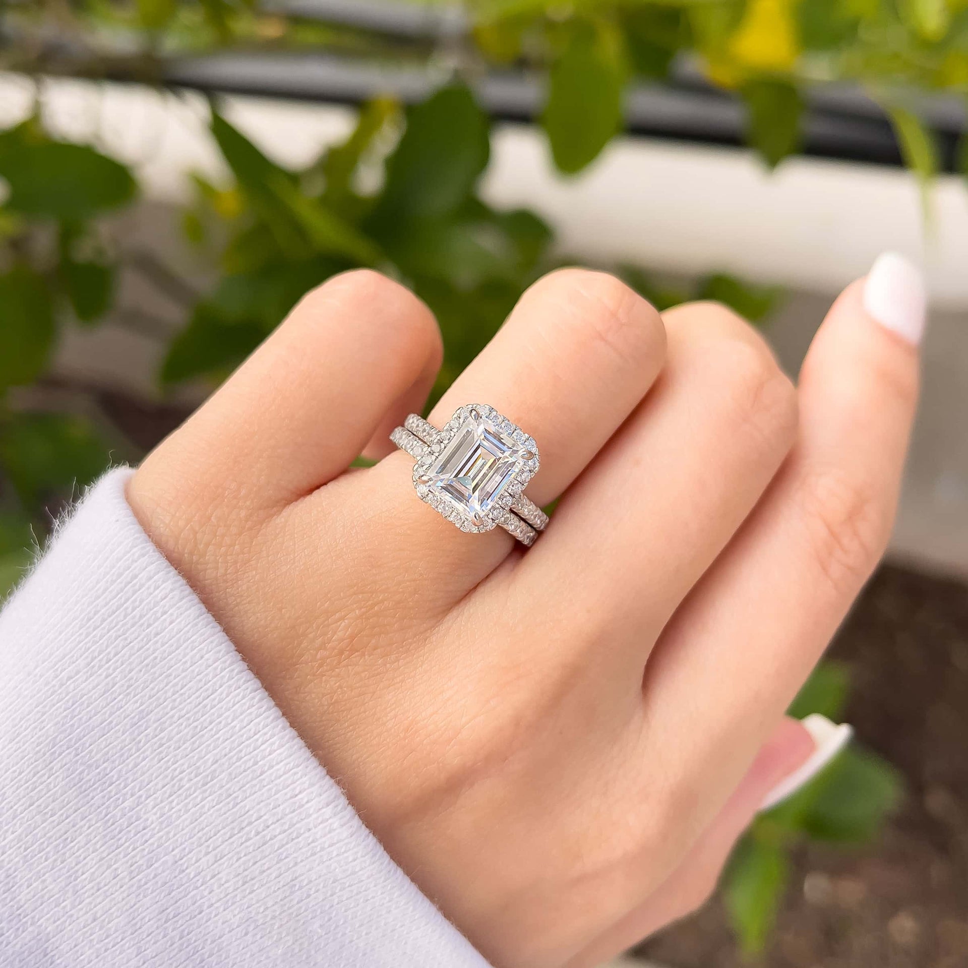 3 carat emerald cut engagement ring shown in silver paired with a stunning silver wedding band shown on model