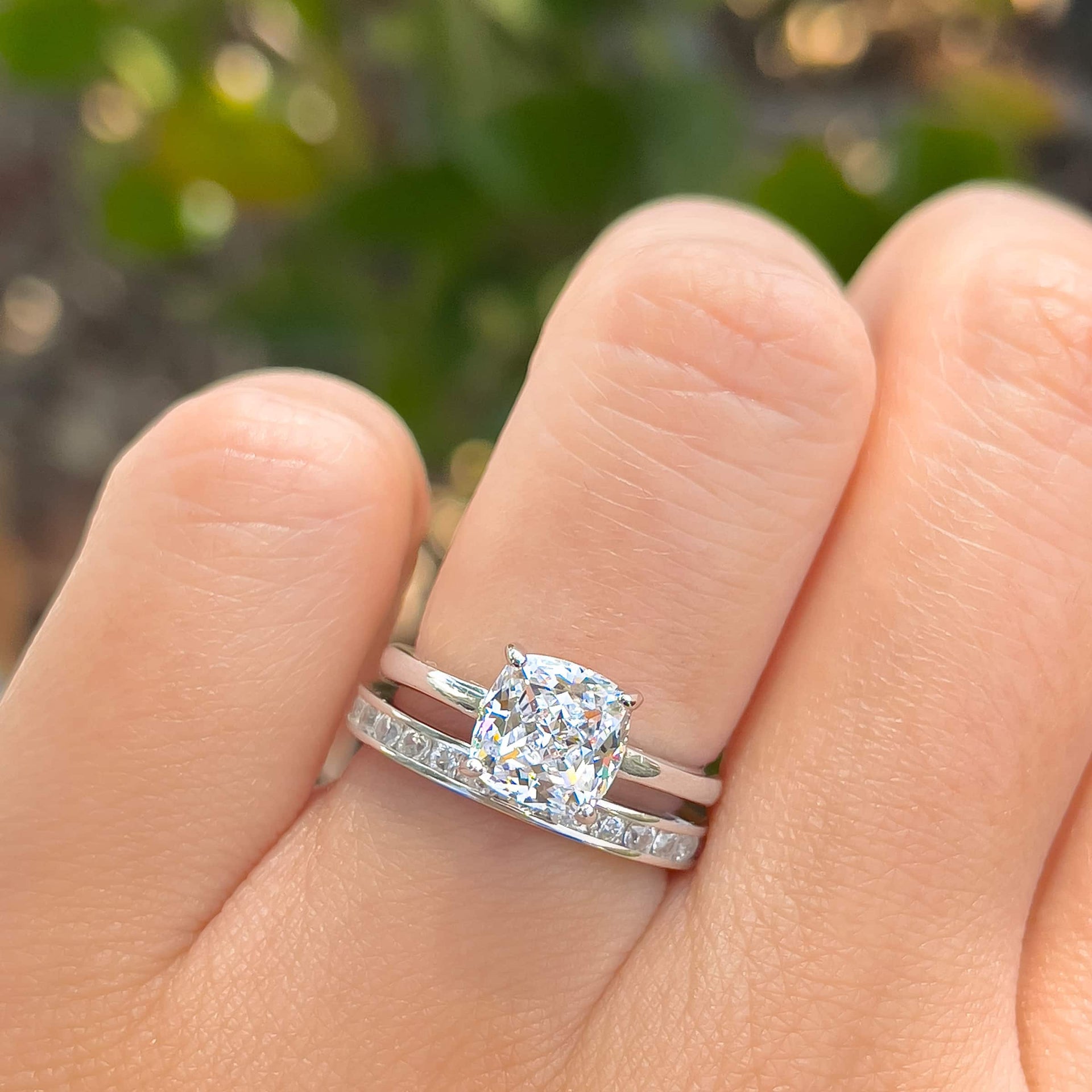 Classic 1 carat cushion cut solitaire engagement ring paired with sleek eternity wedding band modeled on female hand