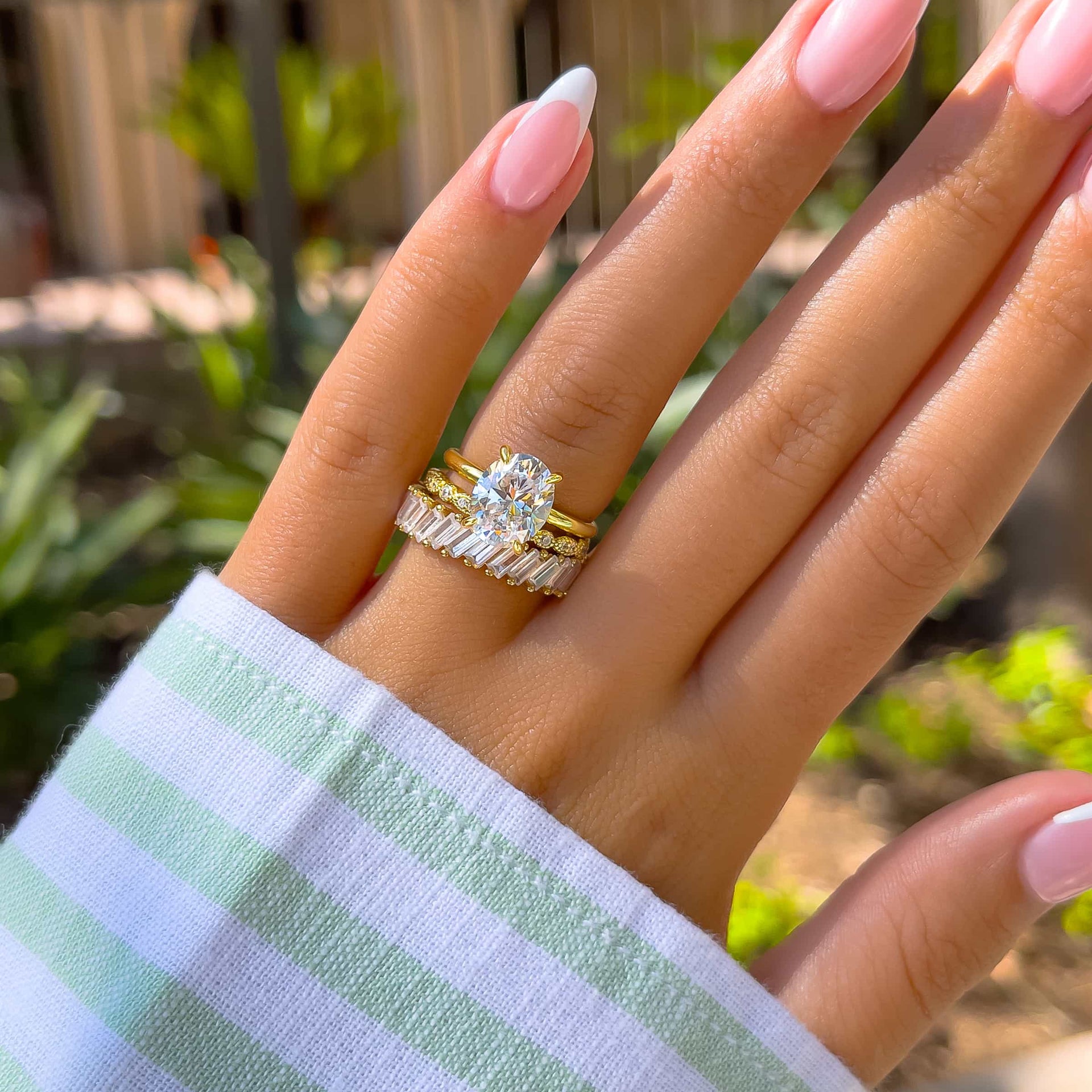 gorgeous 3 carat oval shaped engagement ring on woman's hand with vintage wedding band and artemis band