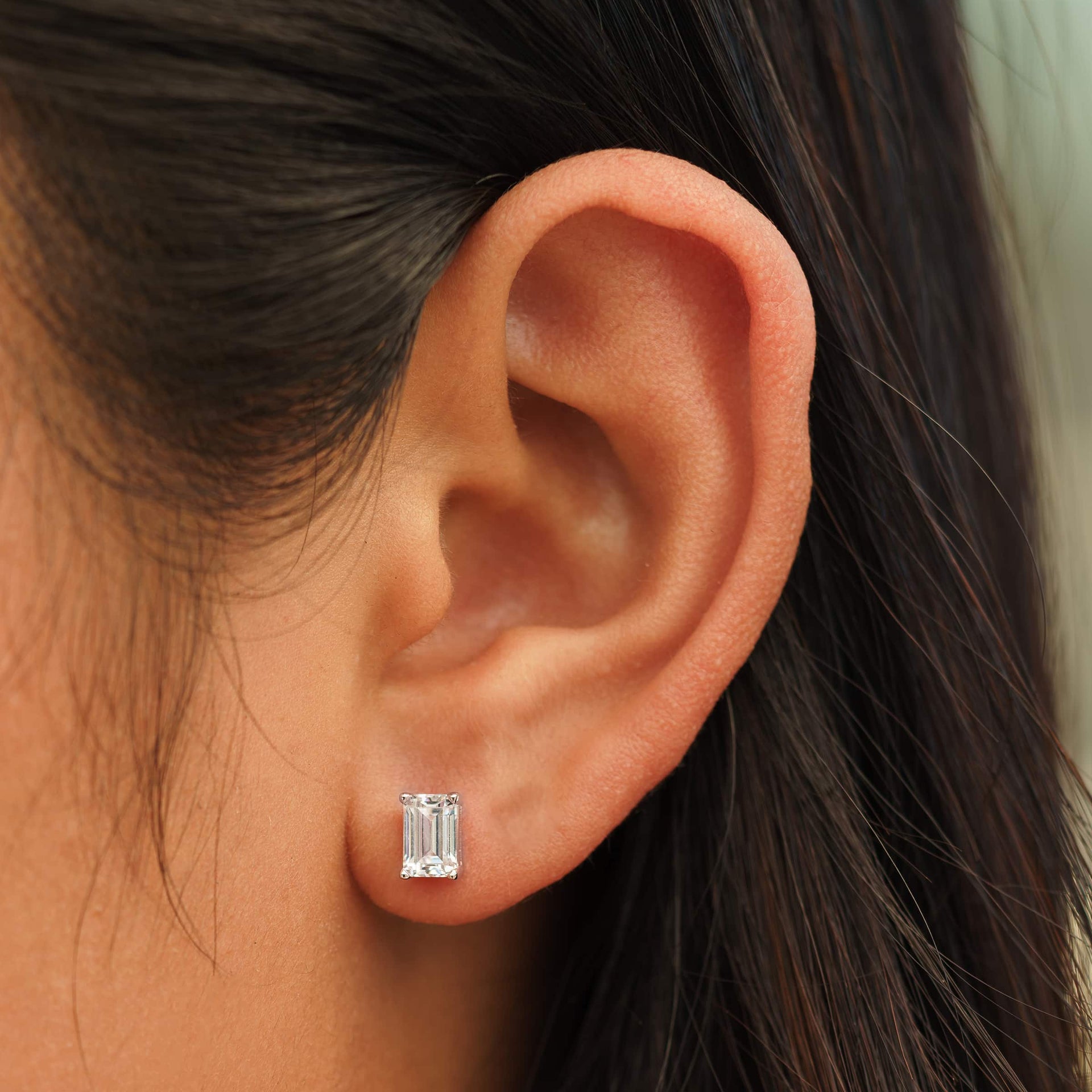 small silver emerald cut stud earrings on female model