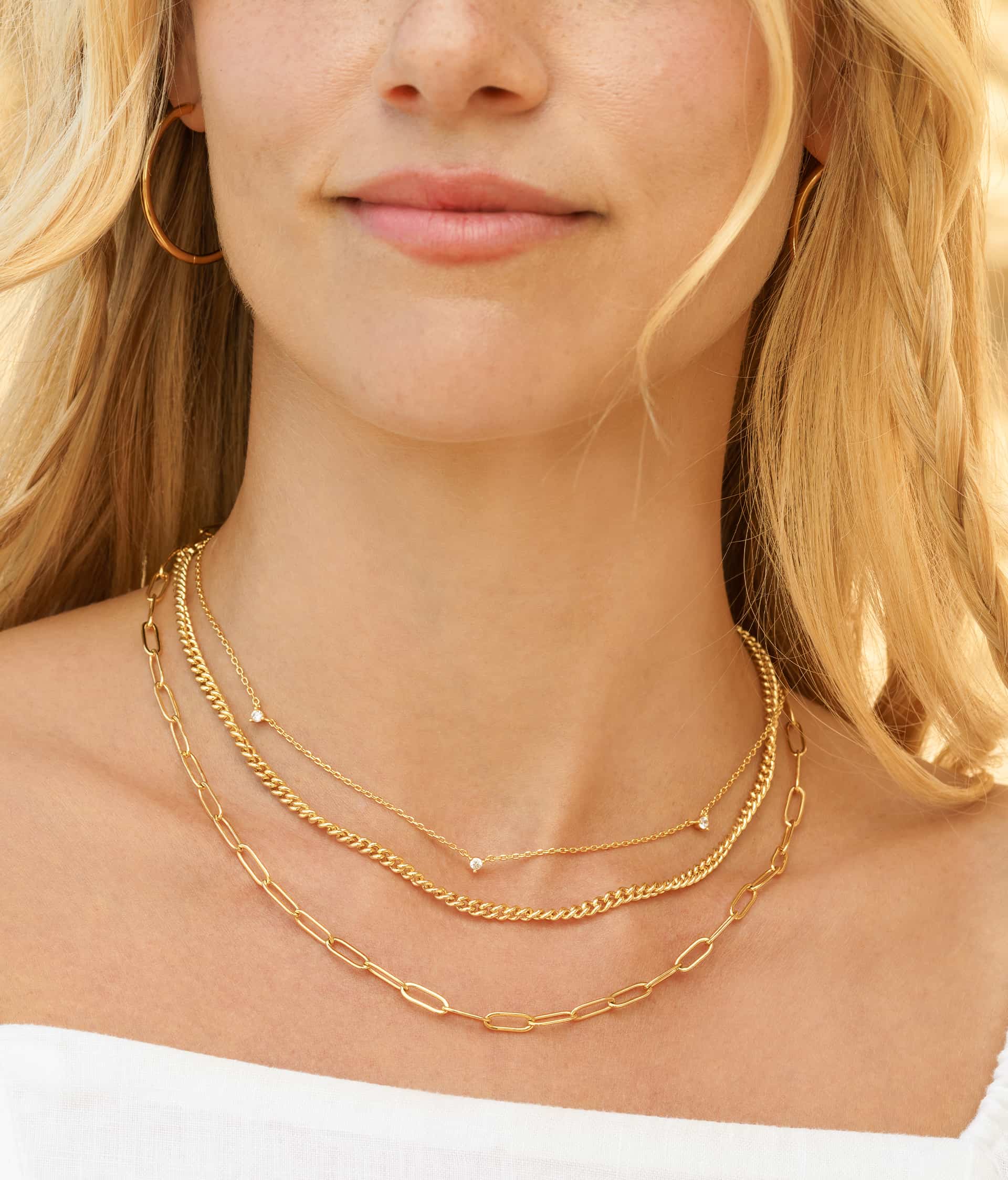 woman wearing gold necklace stack with gold earrings