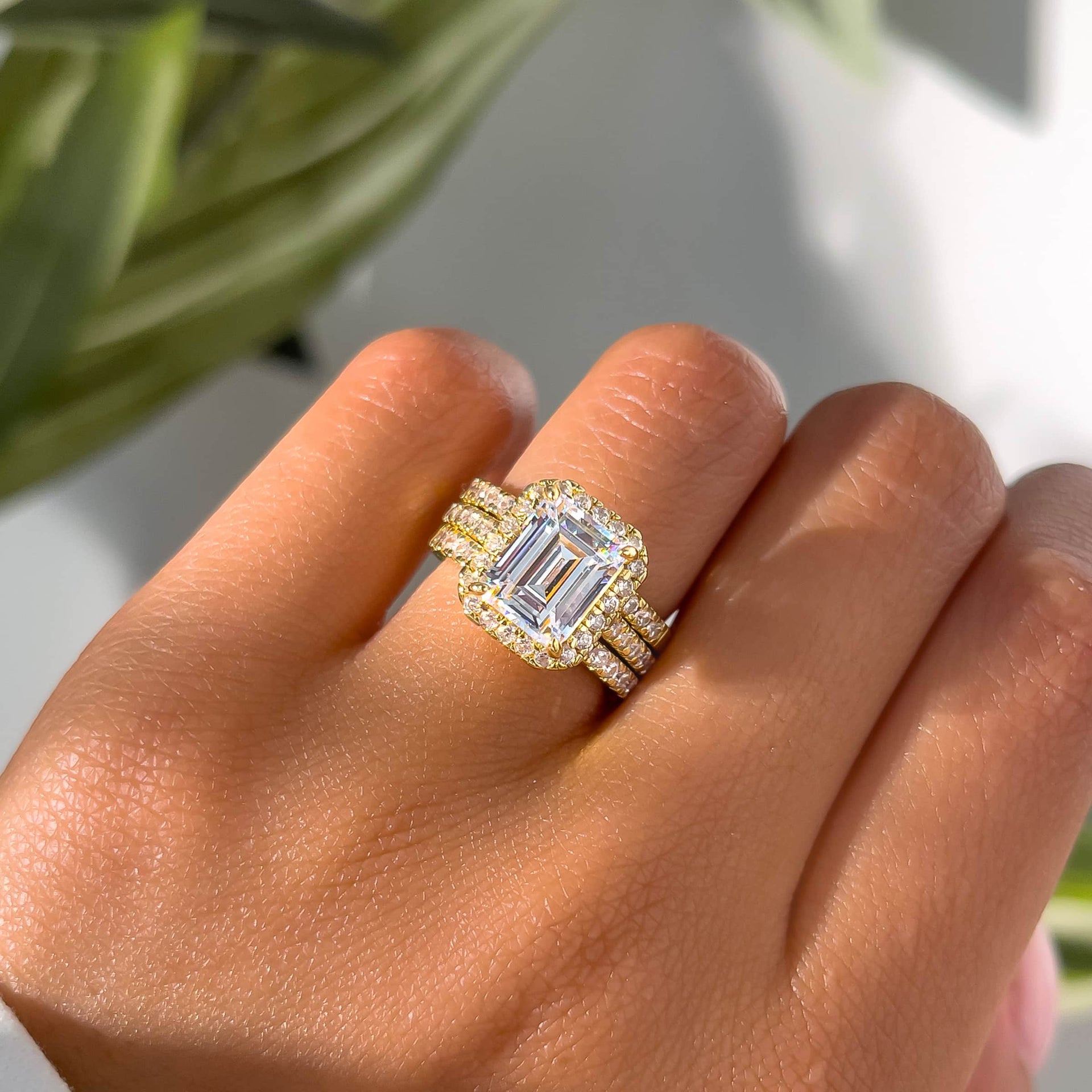 gorgeous gold emerald cut halo engagement ring with gold wedding bands to match on model