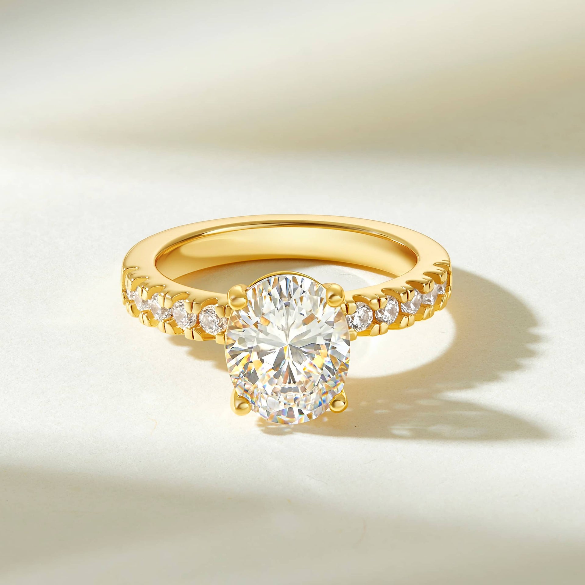 gold 3 carat oval cut half eternity engagement ring on a cream colored background