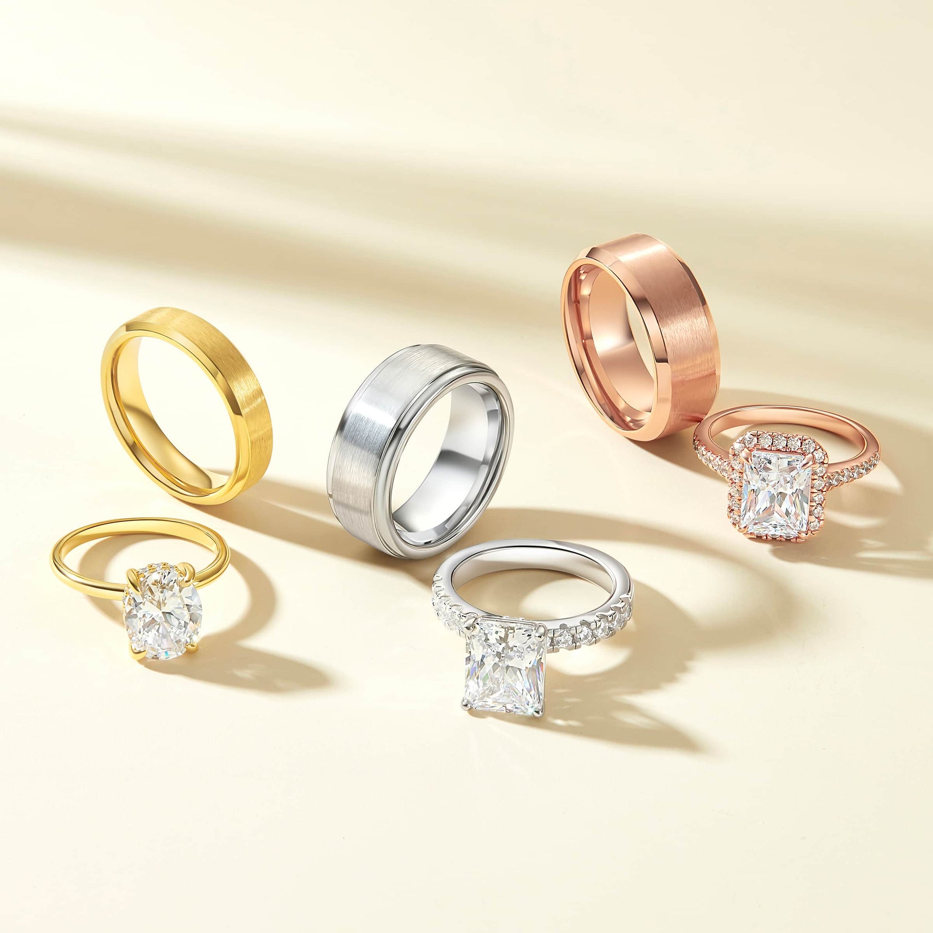 stunning engagement rings and men's wedding bands shown in gold, silver, and rose gold on a cream colored background