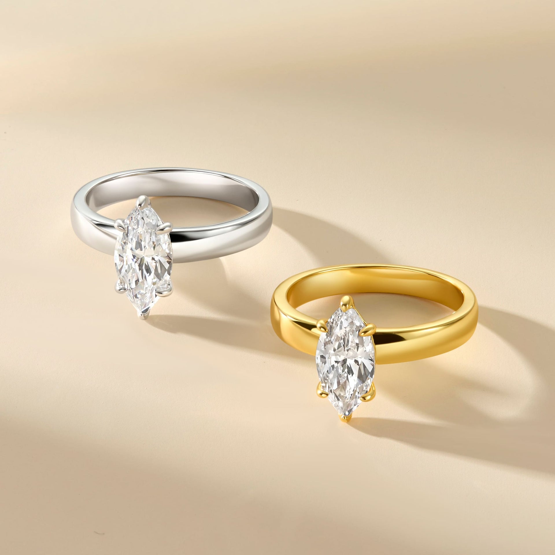 a 2 carat marquise cut 3mm solitaire engagement ring shown in both silver and gold on a light tan background
