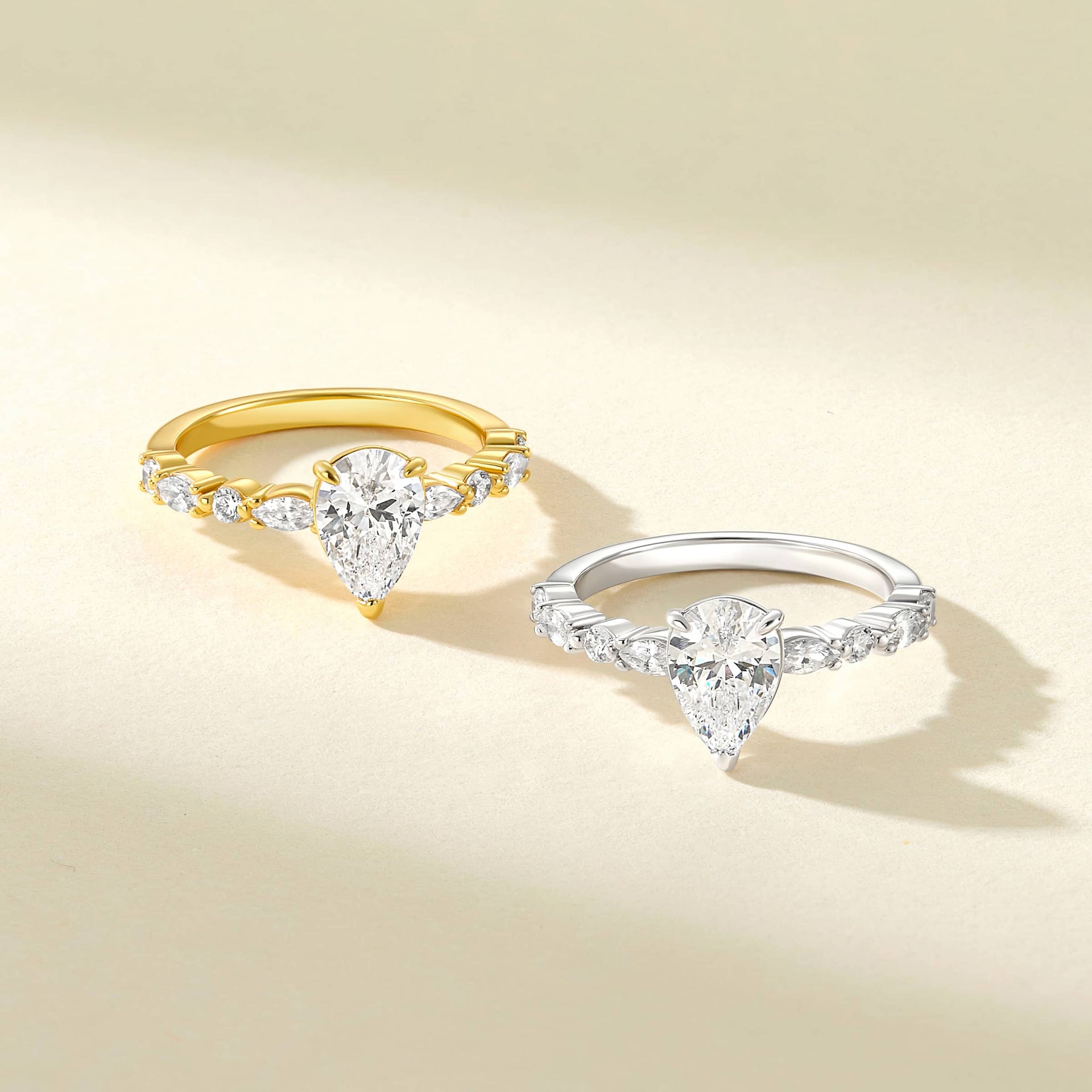 vintage style 1.5 carat pear cut half eternity engagement ring shown in gold and silver on an off-white background