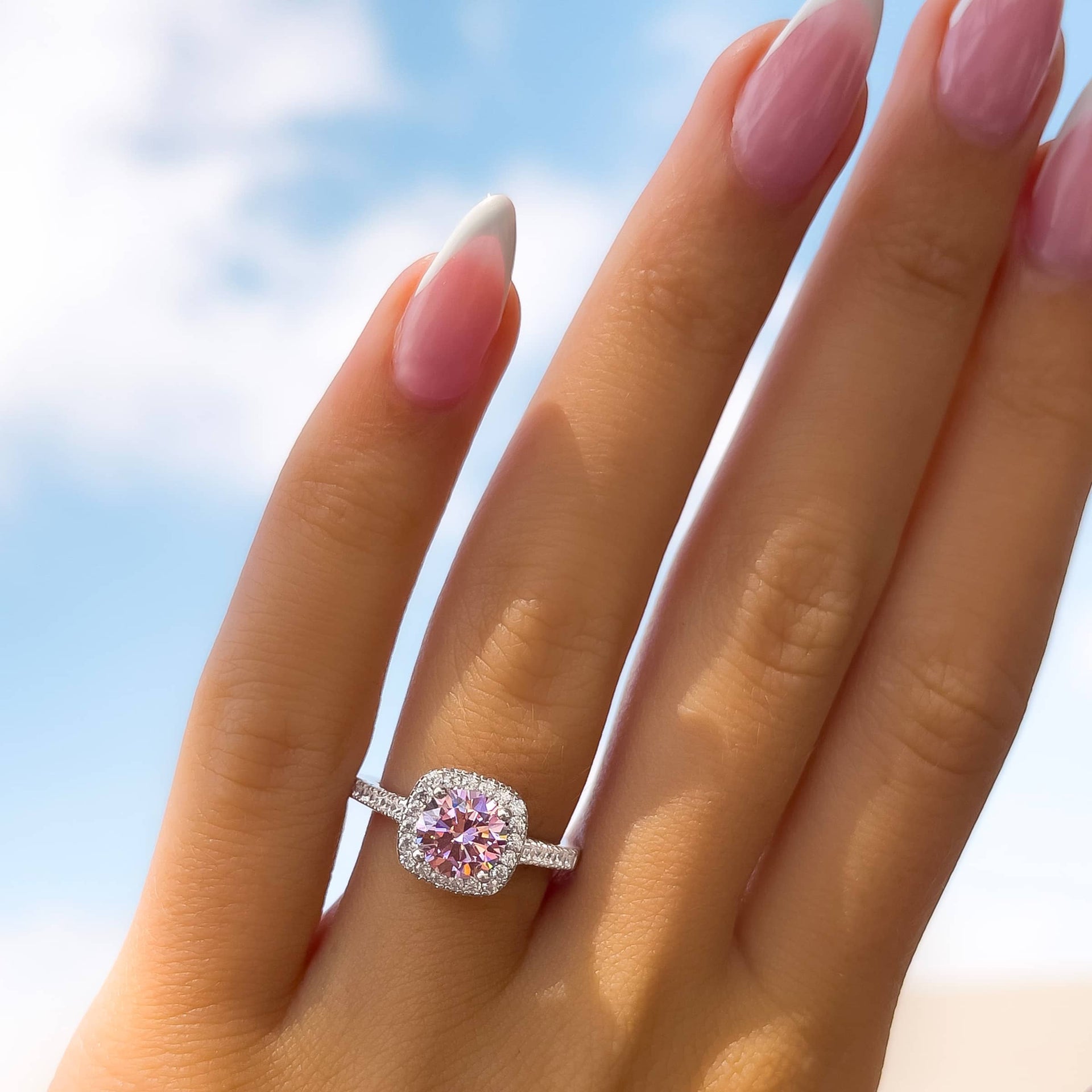 classic round cut pink sapphire engagement ring on female model with french tip nails