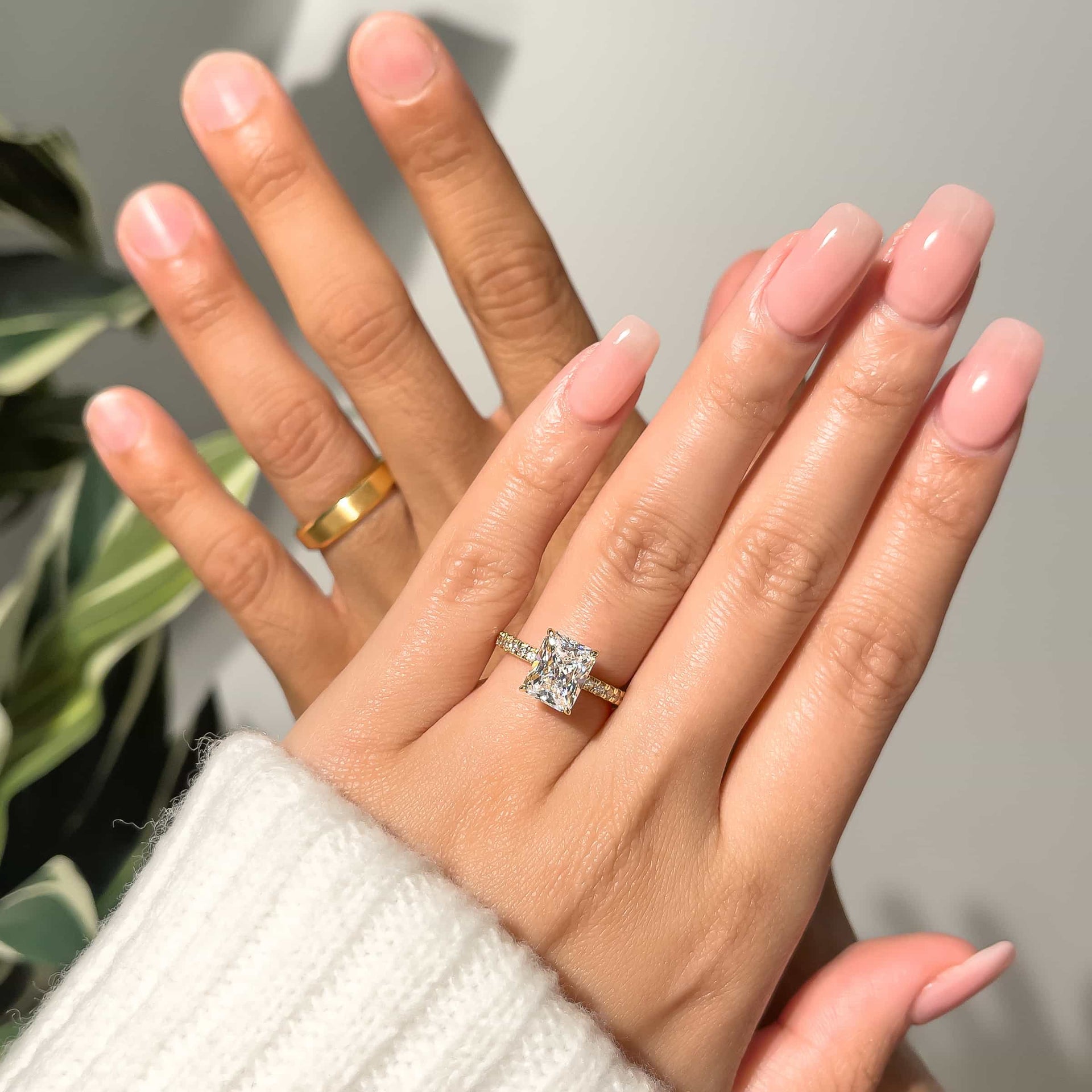 Couple wearing beautiful gold radiant cut engagement ring with infinity wedding band in gold