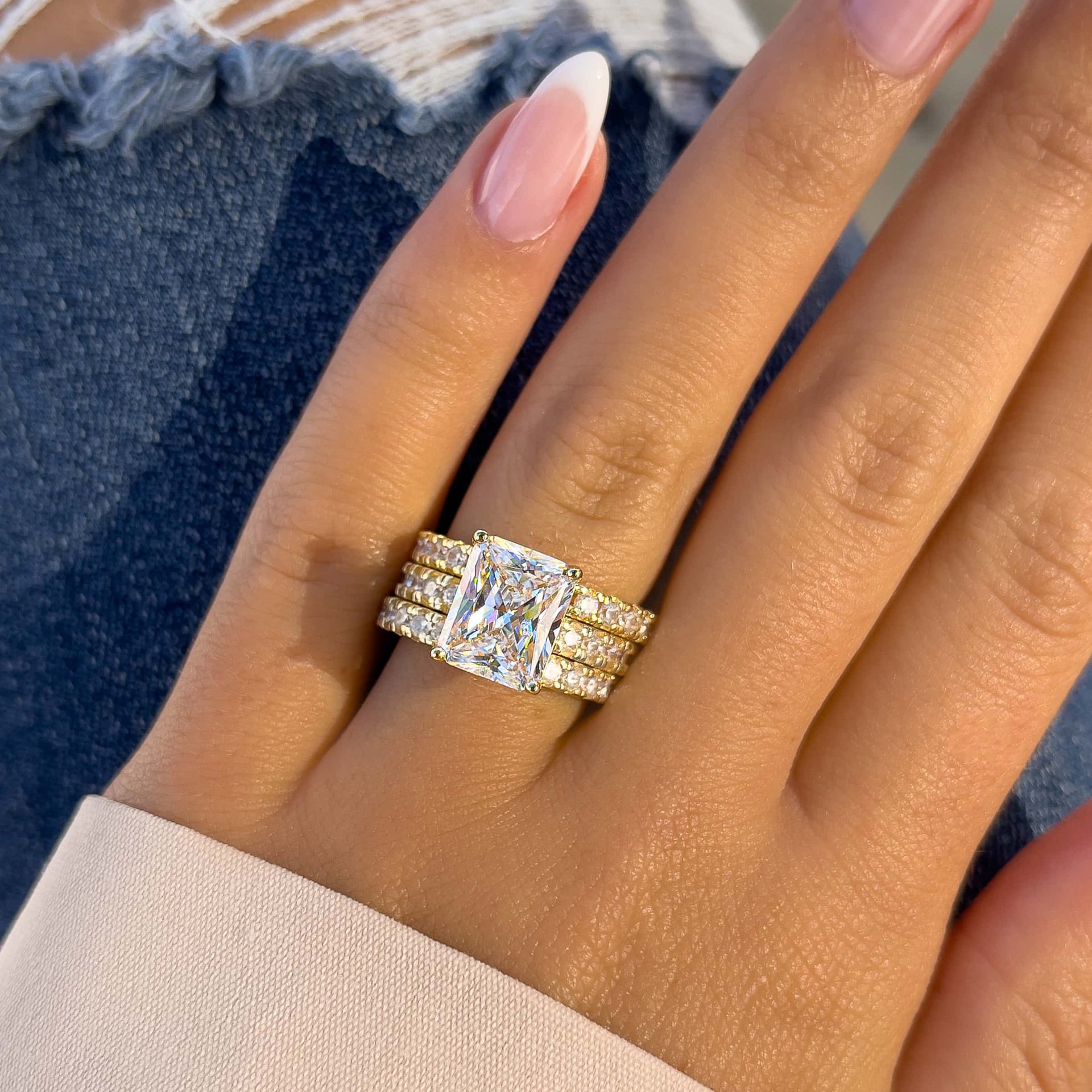 bold gold triple wedding ring stack on model with french tip nails and jeans