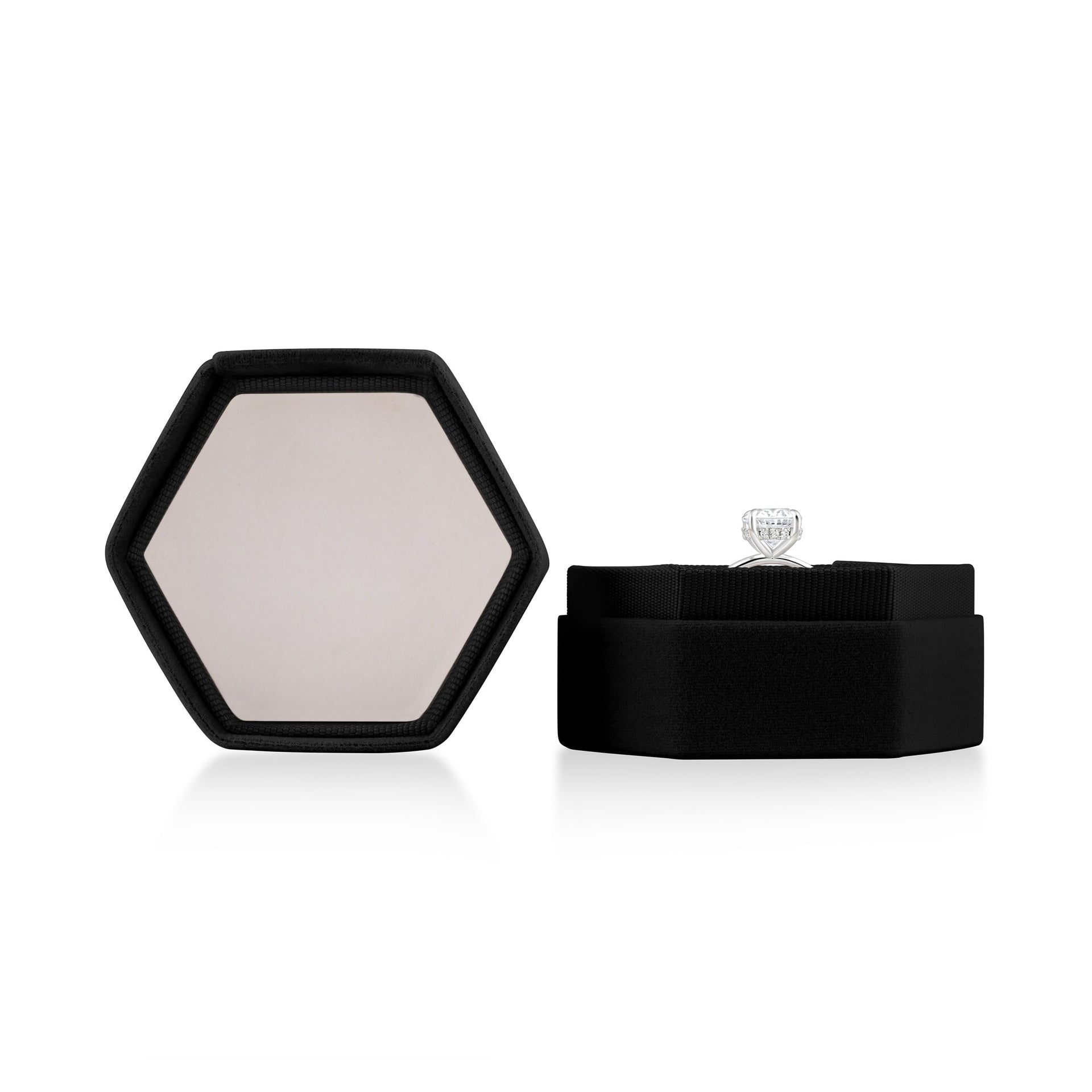 Black hexagon velvet ring box shown opened with a silver engagement ring inside on white background