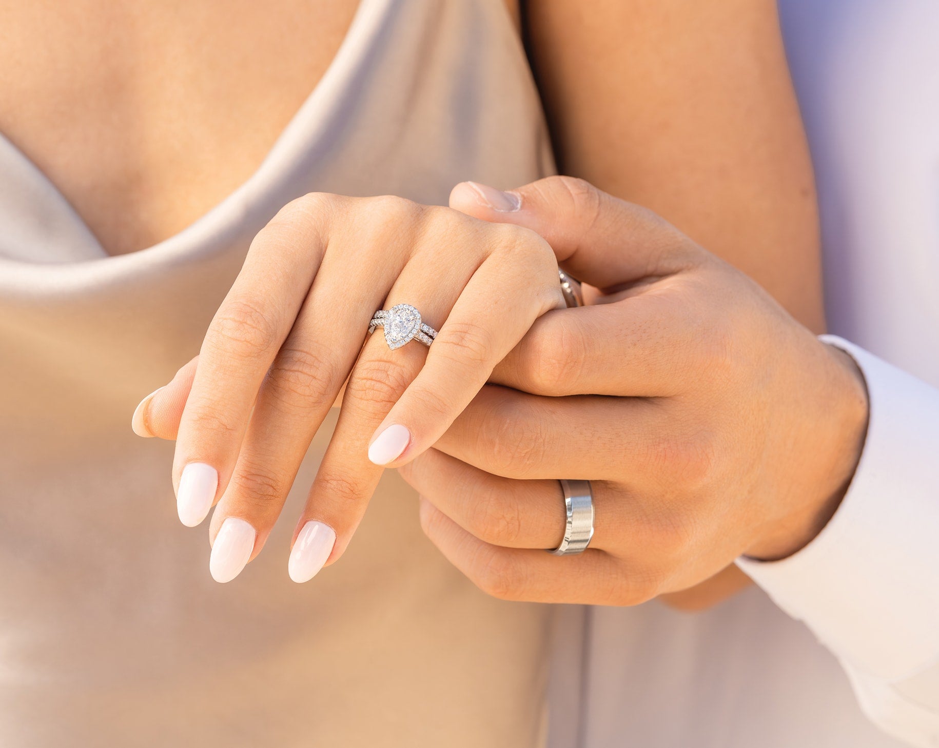 couple holding hands wearing silver wedding ring set with silver men's band