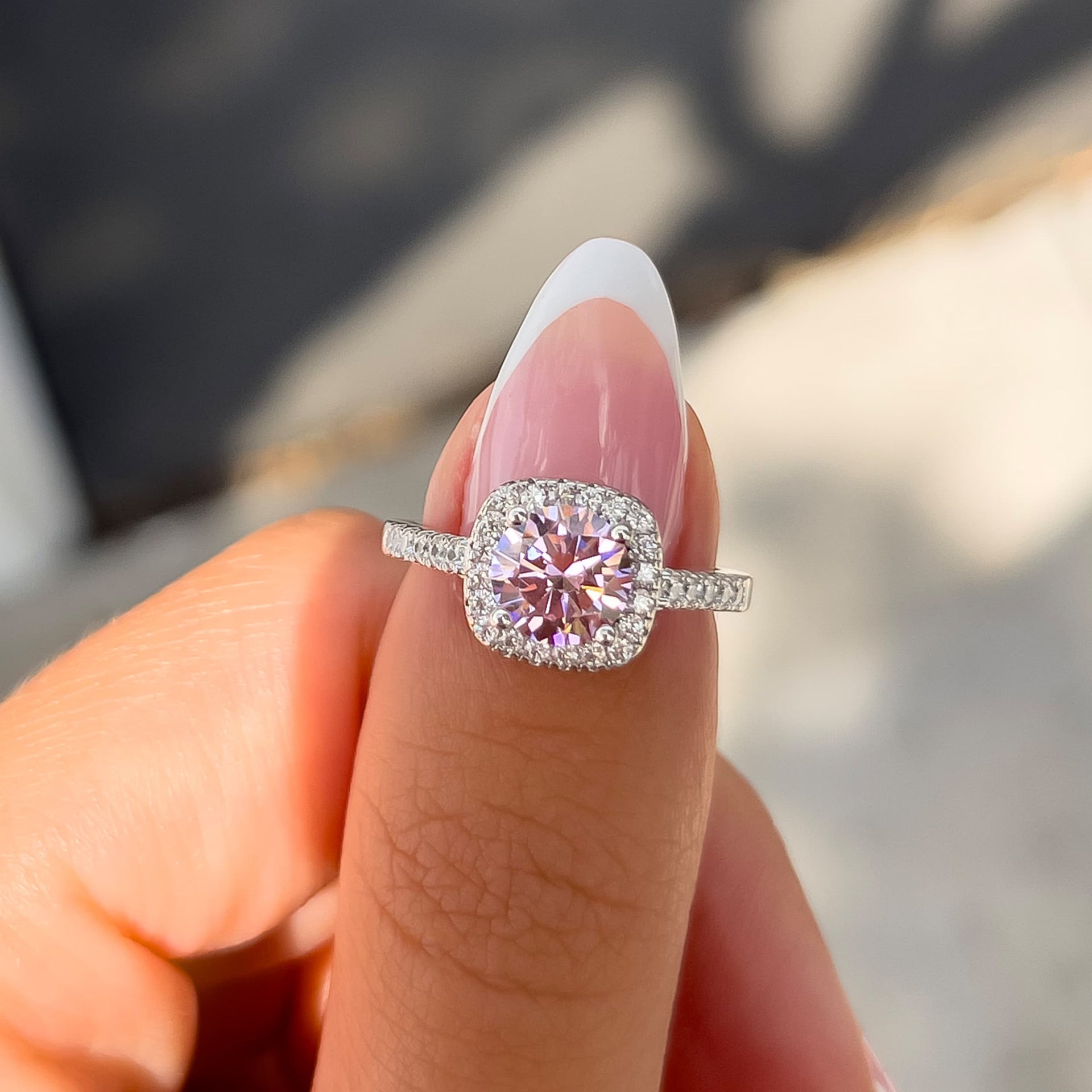 1.5. carat round cut pink sapphire engagement ring on thumb with french tip nail