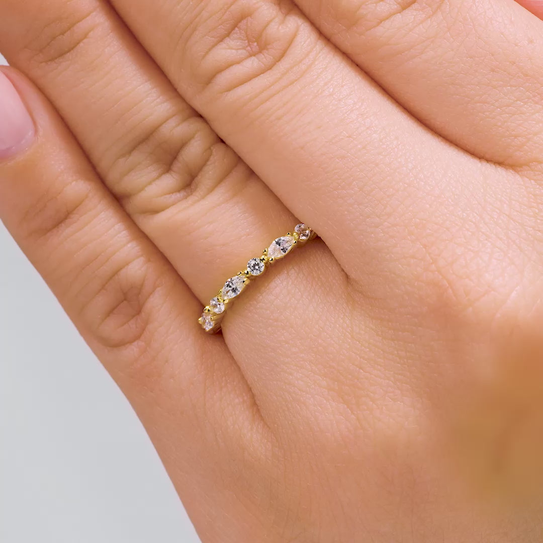 gold wedding band with round and marquise stones worn by model on white background