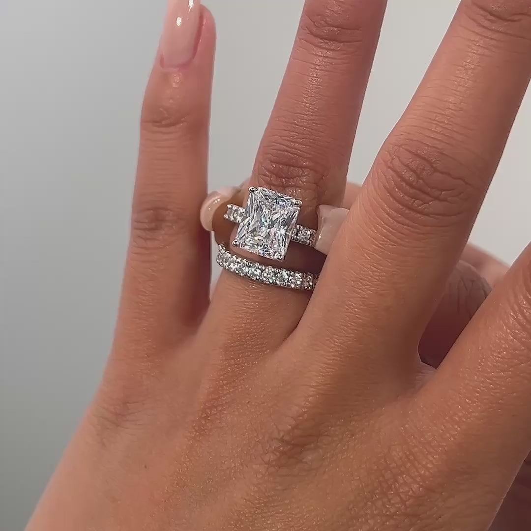 video of silver radiant cut wedding ring set on model with neutral nails
