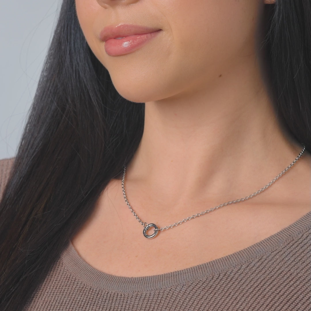 video of a dainty silver stainless steel cable chain charm necklace on a female model